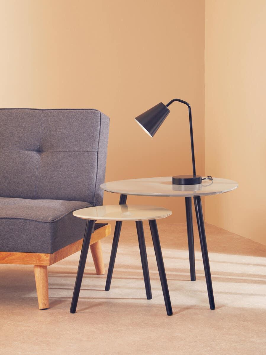 Nesting coffee tables with black legs and beige tops beside grey sofa and black table lamp