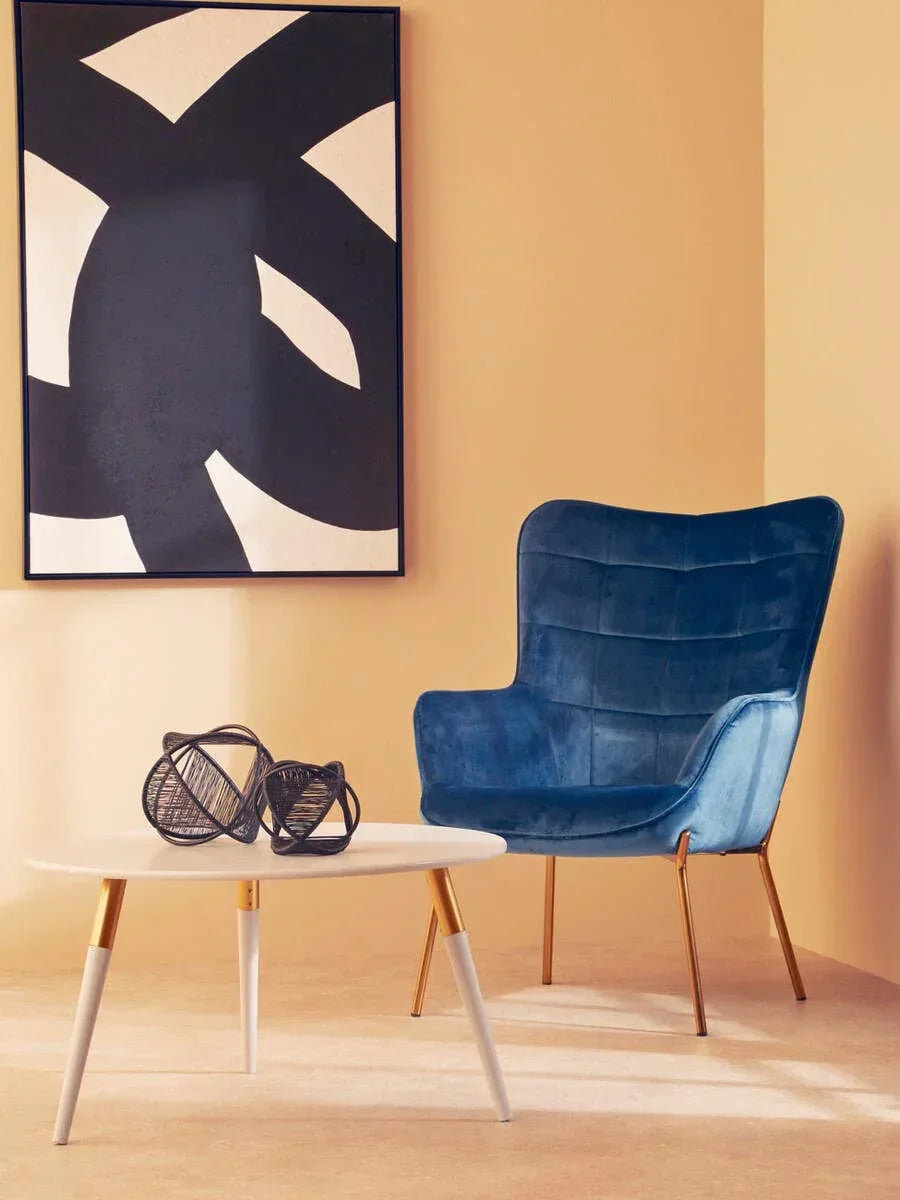Blue velvet accent chair with gold legs beside modern white coffee table in minimal living room