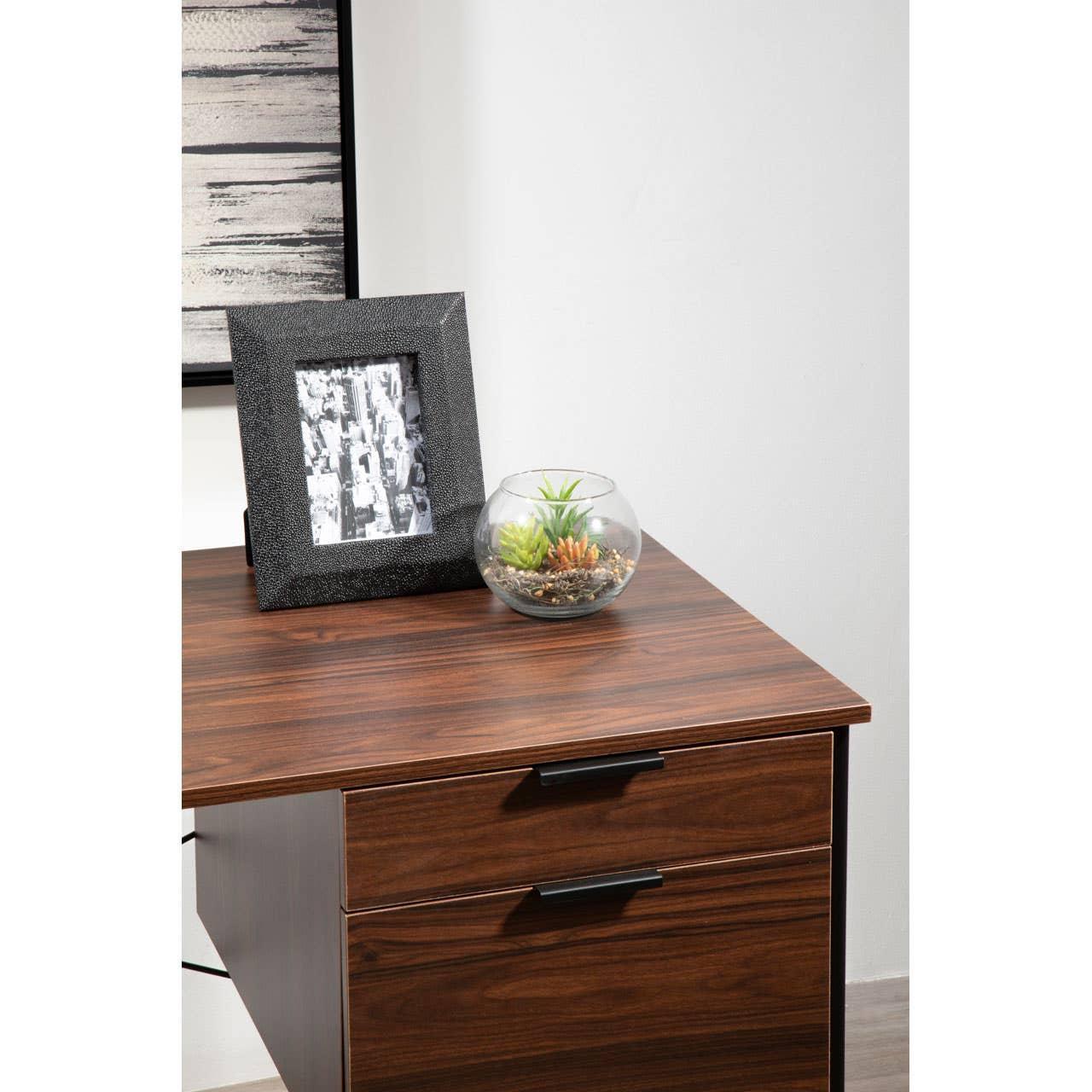 Walnut finish office desk with black drawer handles, photo frame and glass plant terrarium