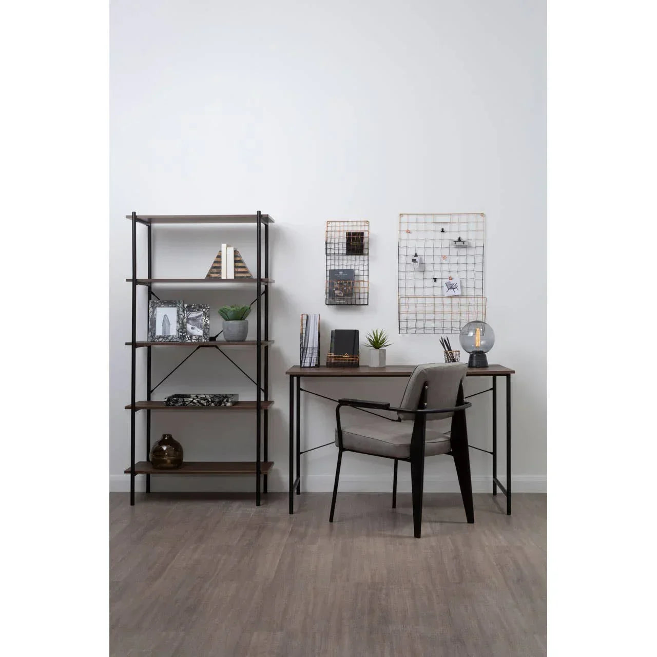 Home office desk with chair, shelving unit, and decorative accents on wood floor