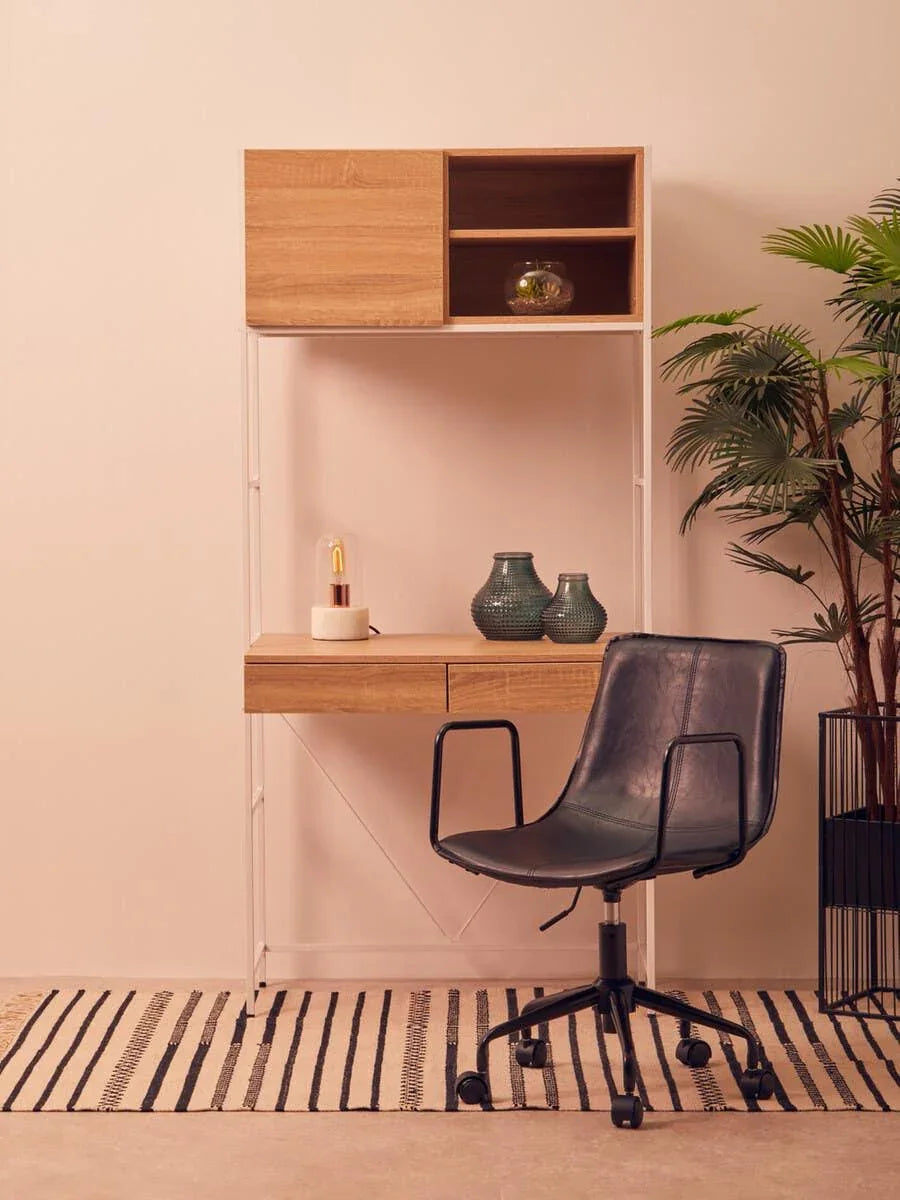 Wooden home office desk with shelving, black chair, and indoor plant on striped rug