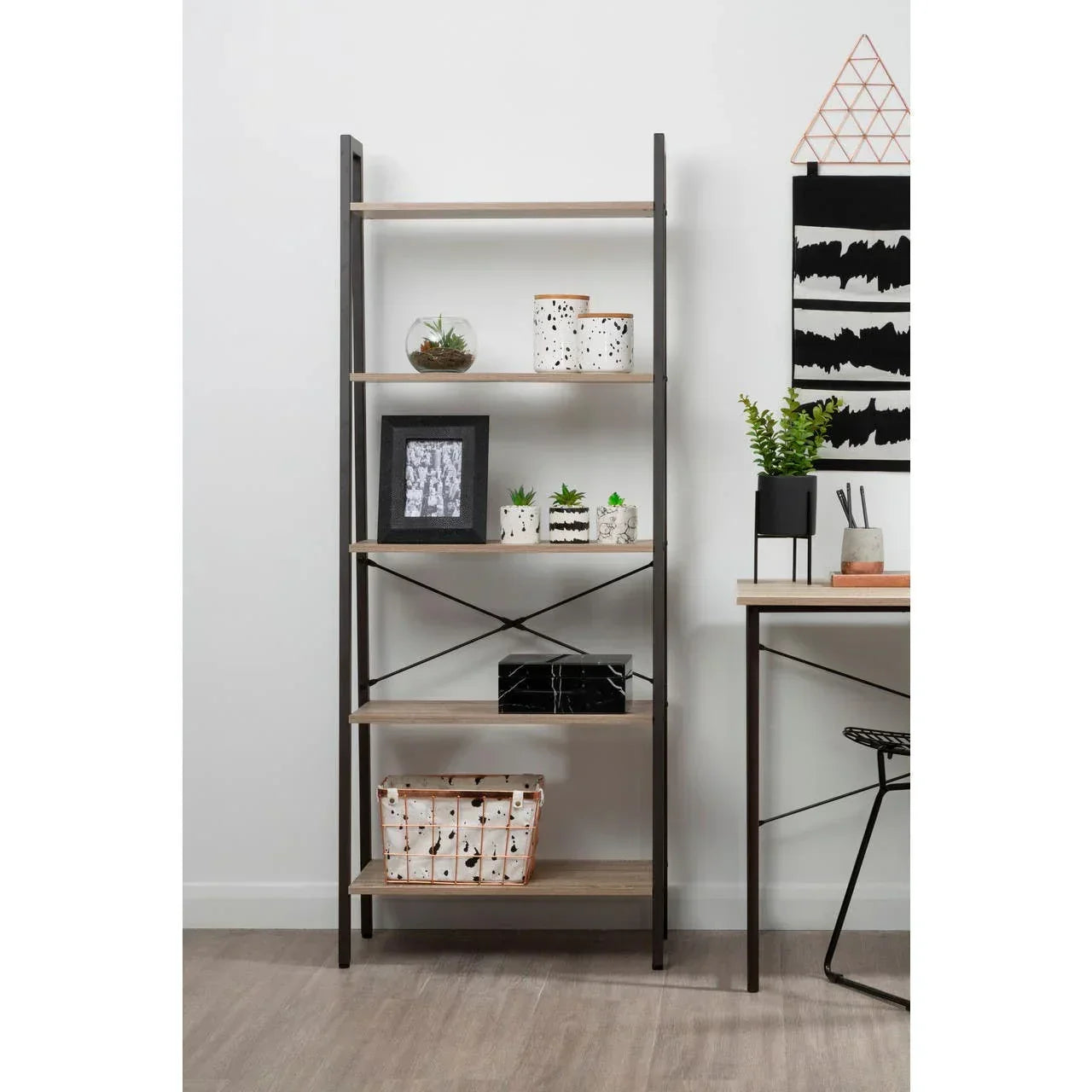Industrial bookshelf with wooden shelves and black frame styled with plants and decor