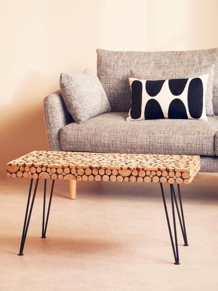 Wood slice coffee table with black metal hairpin legs in front of a grey fabric sofa