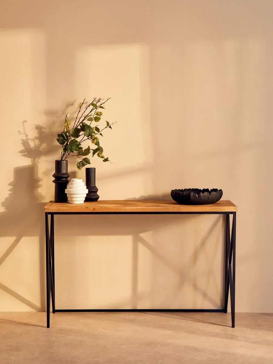 Industrial console table with wooden top, black metal legs, and decorative vases in sunlight