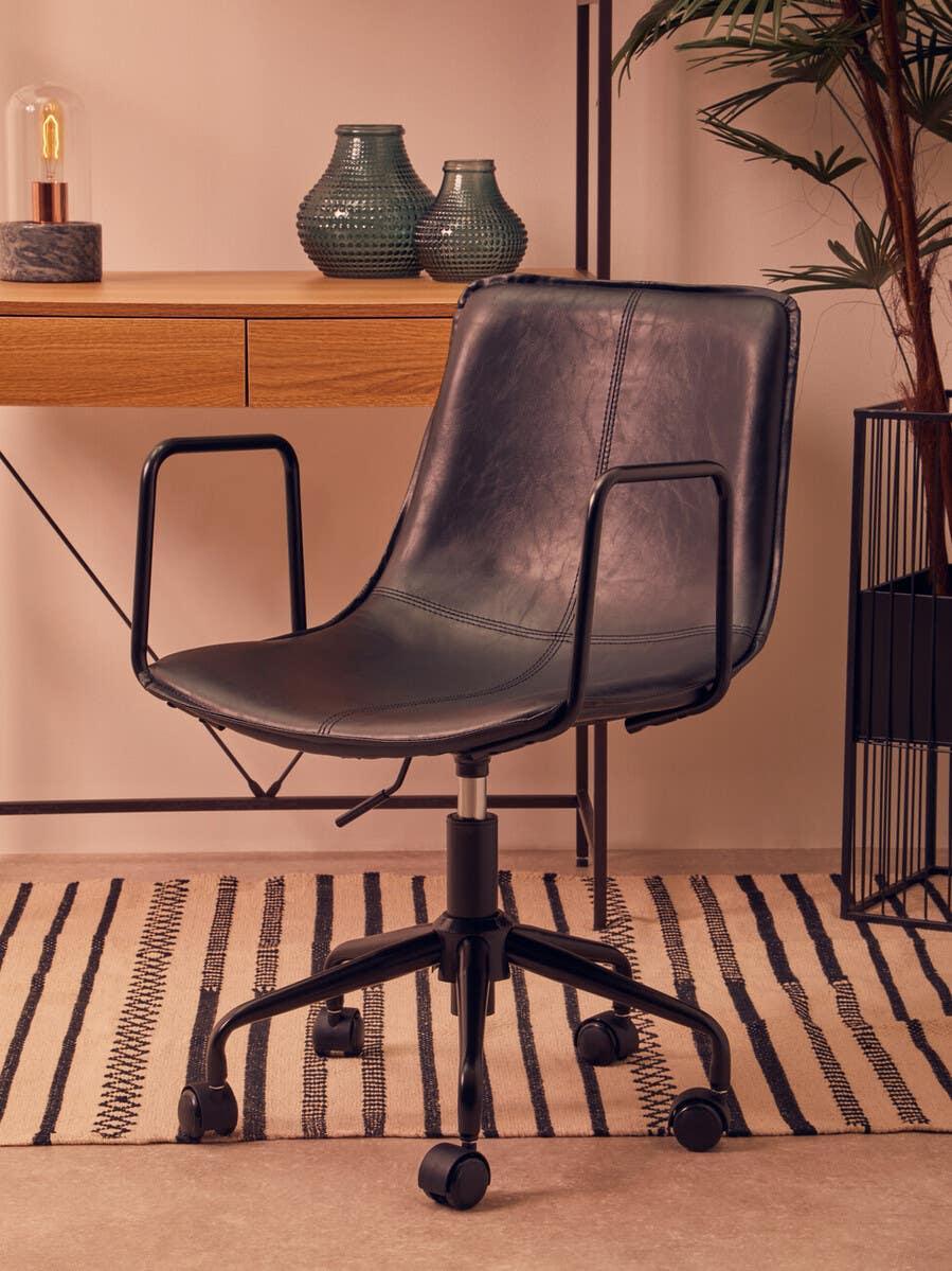 Black leather office chair with metal arms on castor wheels beside wooden desk