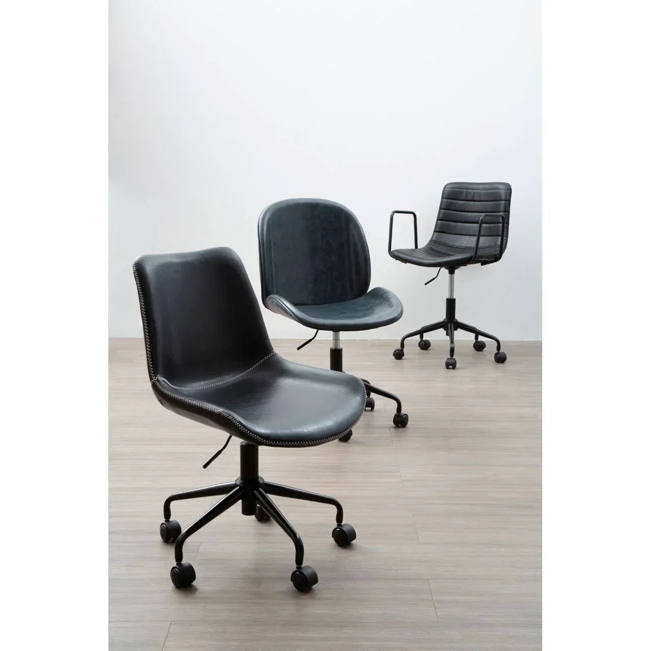 Three black swivel office chairs with wheels on wood flooring, different backrest styles