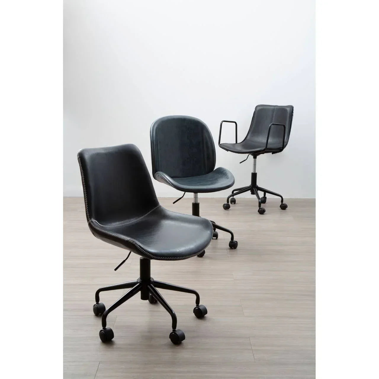 Black swivel office chairs with wheels and armrests on wooden floor