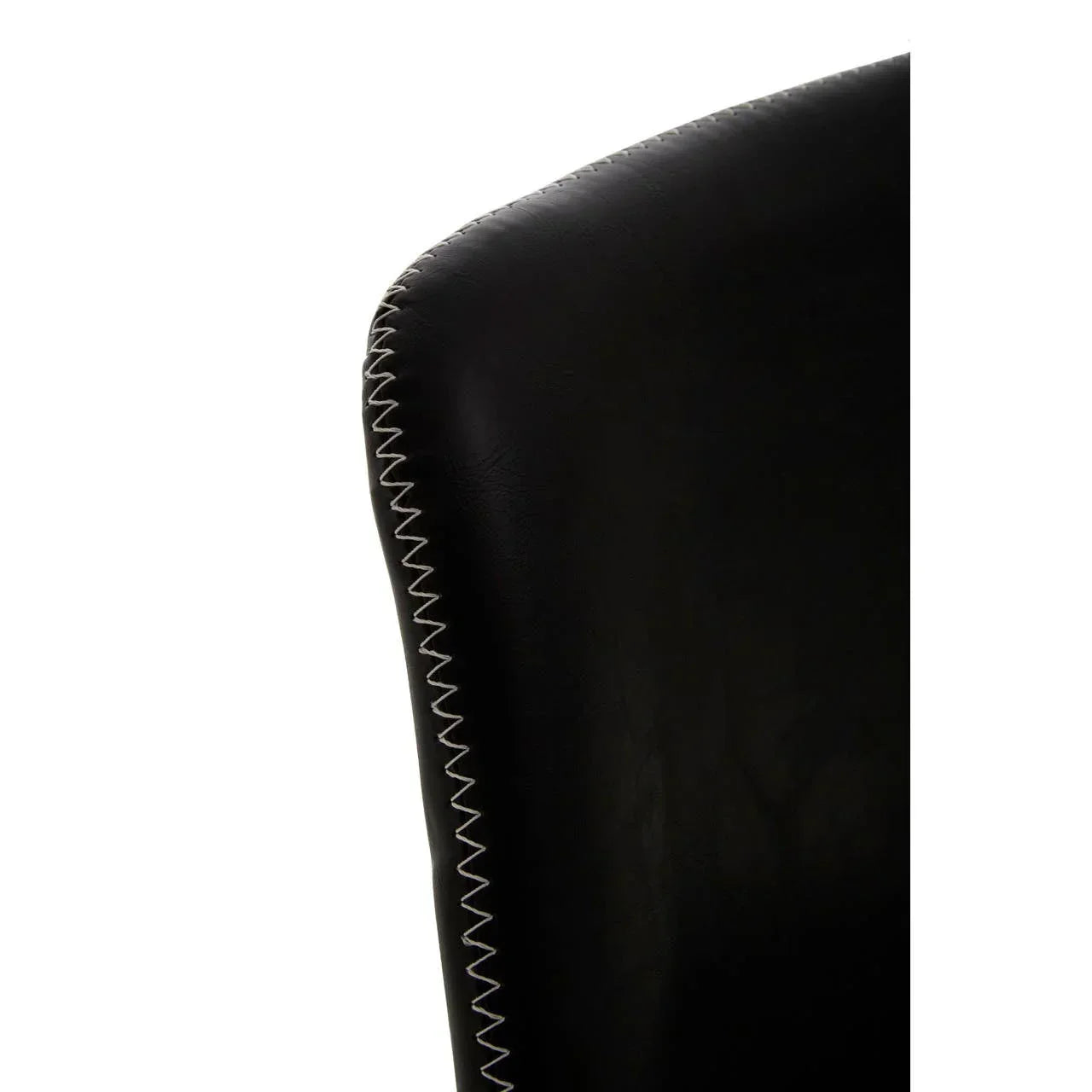 Closeup of black leather dining chair with white zigzag stitching on curved backrest
