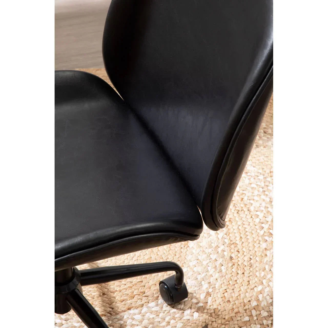 Black office chair with curved backrest and caster wheel on woven rug