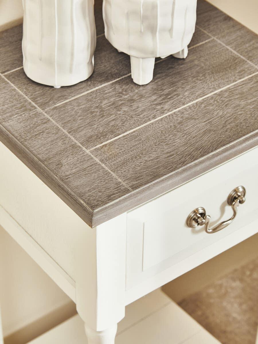 Wooden bedside table with grey top, ceramic vases, metal drawer handle, white finish