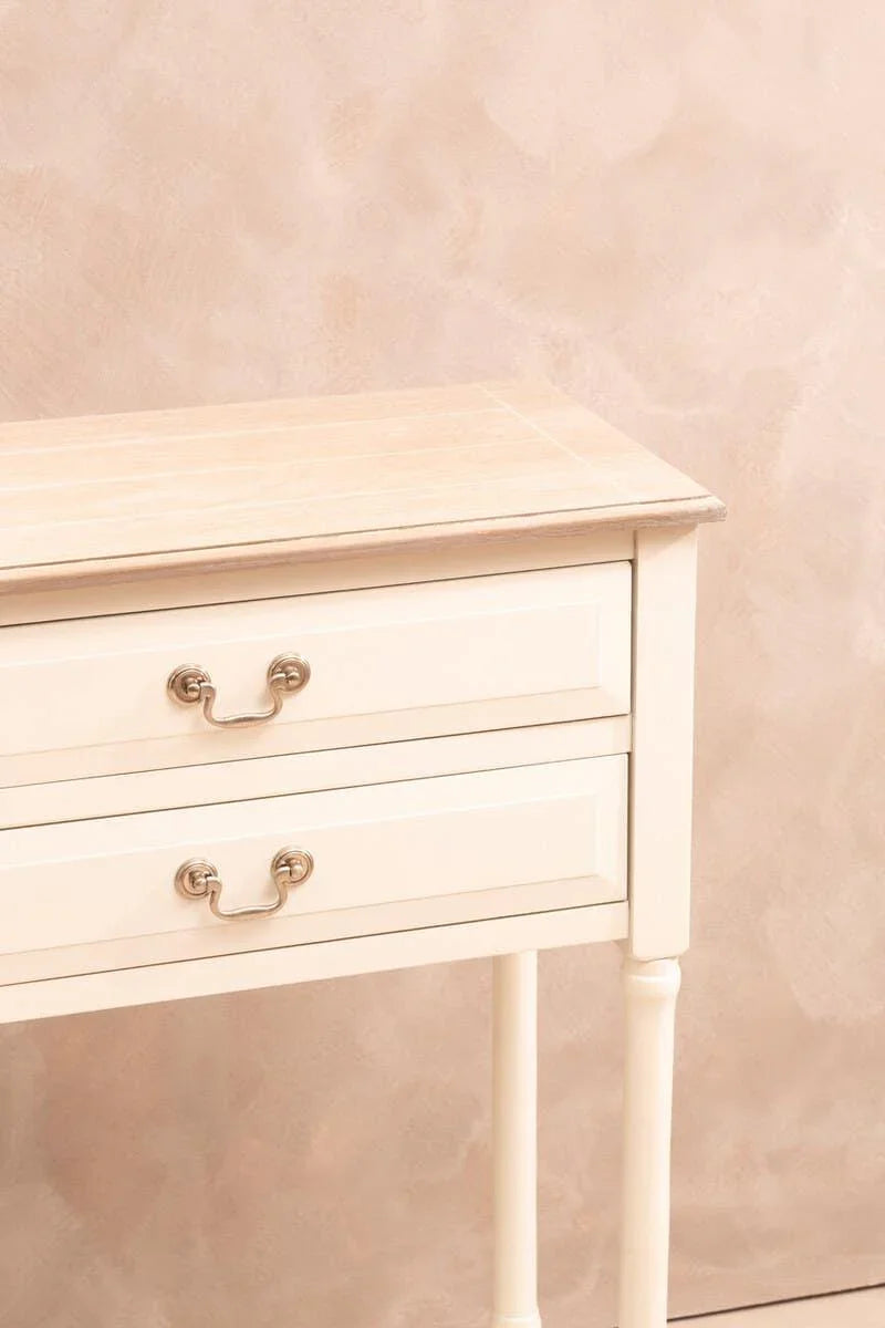 Cream console table with light wood top and two drawers, brass handles, partial side view