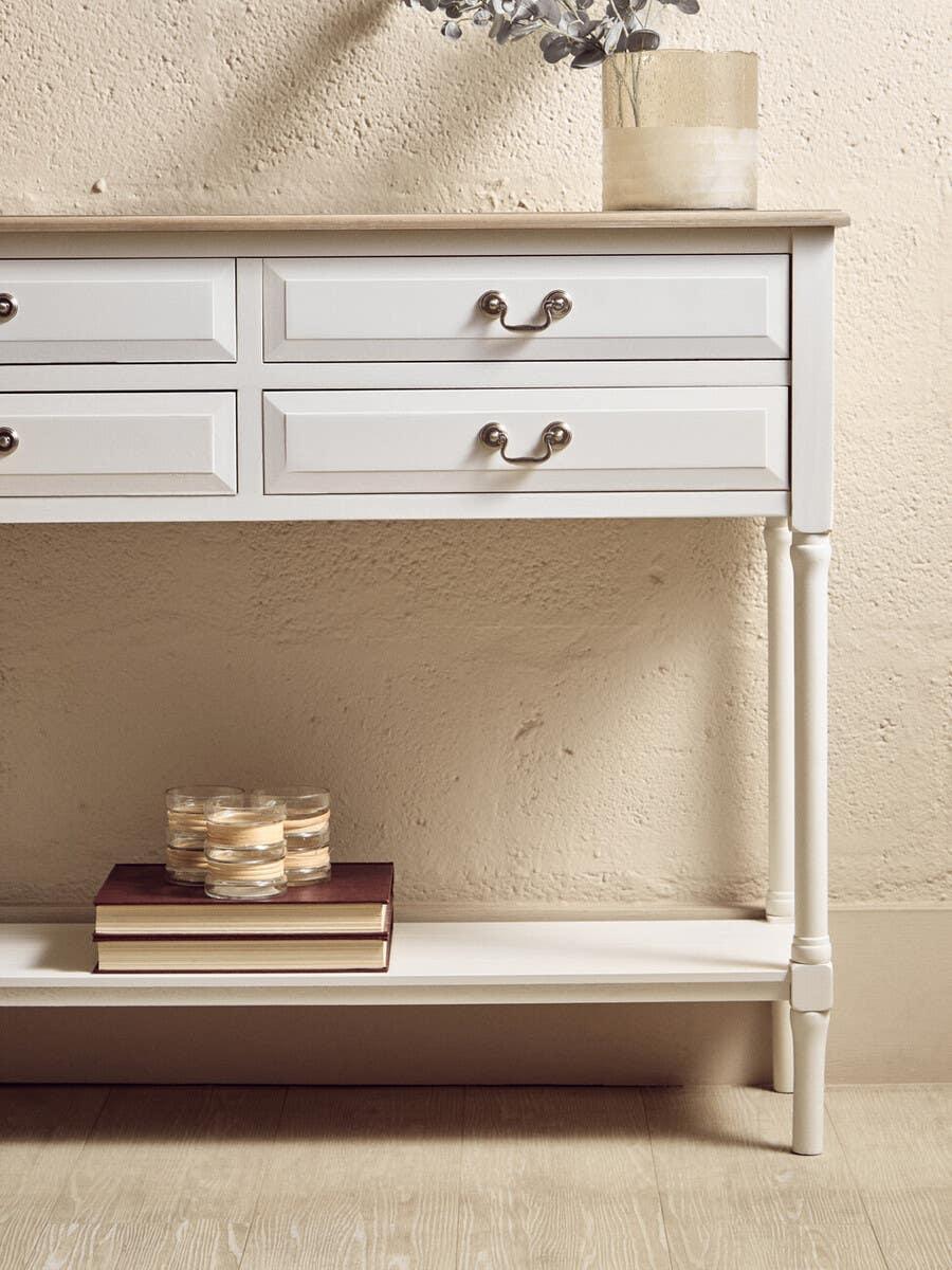 White hallway console table with drawers, glass candle holders, and books on lower shelf