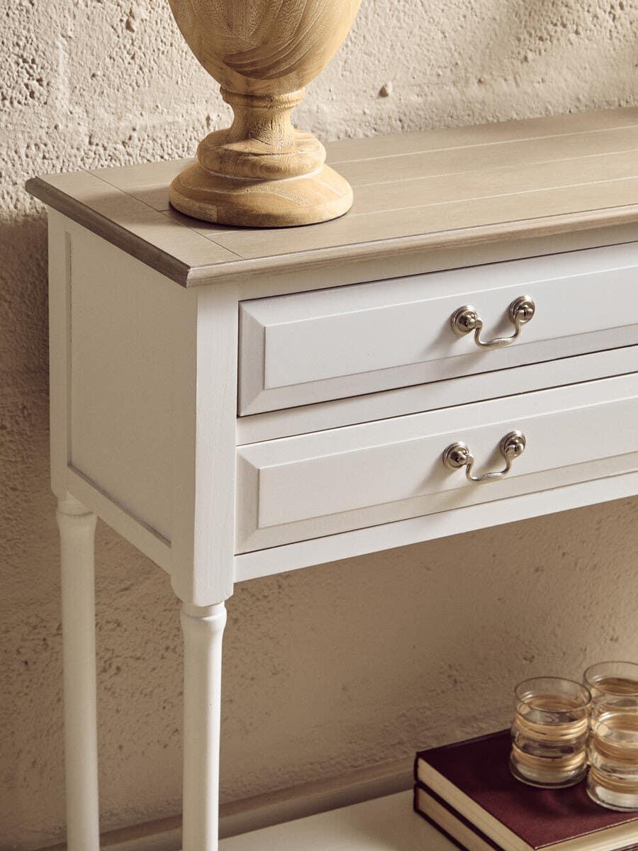 White console table with wooden top, two drawers, and metal handles against textured wall