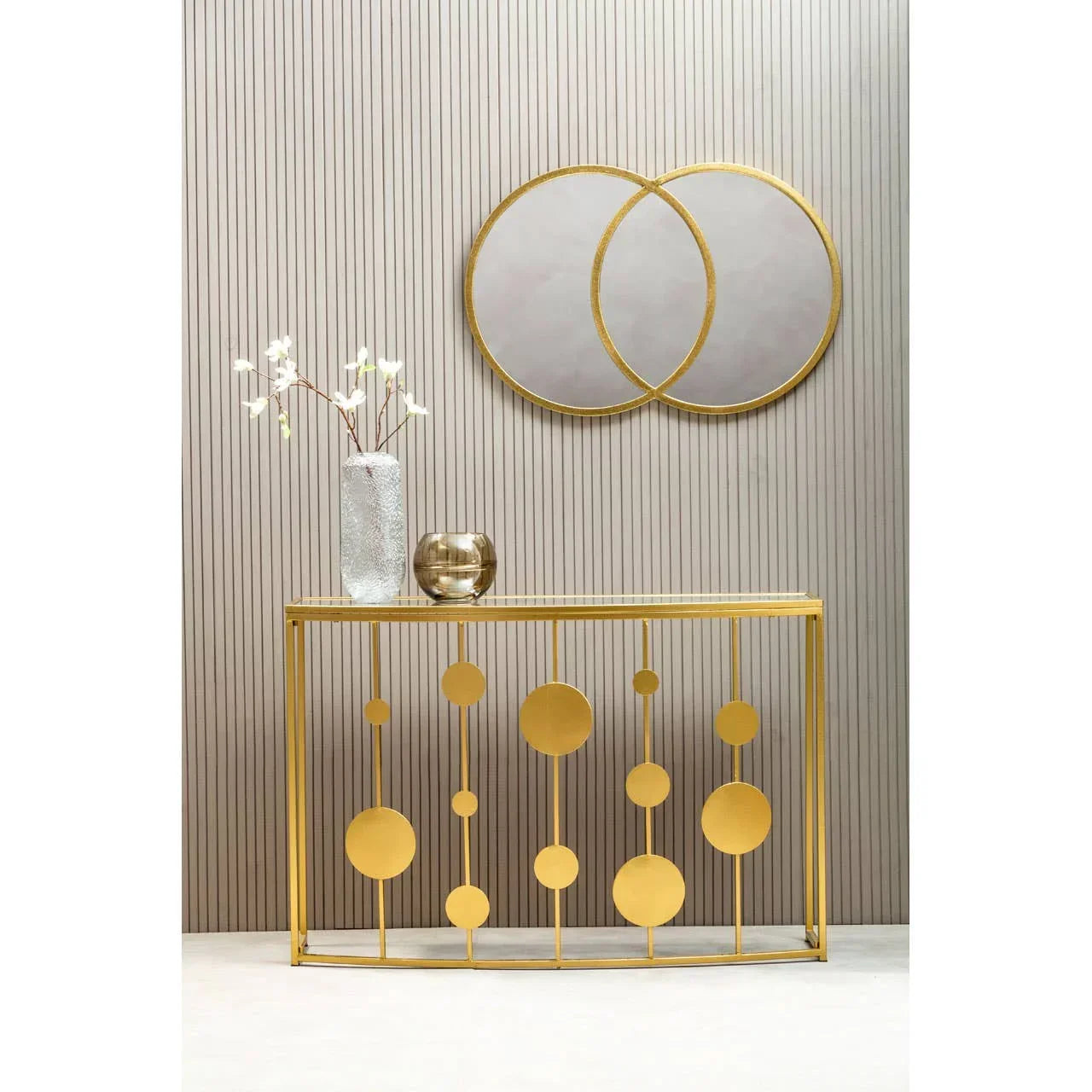 Gold metal console table with geometric circles and decorative vases, wall mirror above