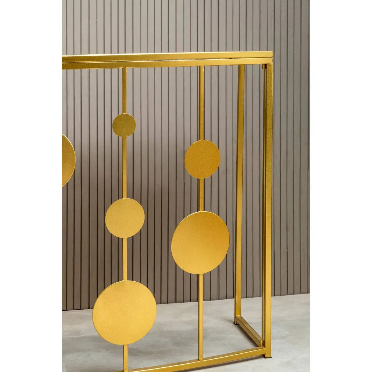 Gold metal console table with circular decorative accents against a paneled wall