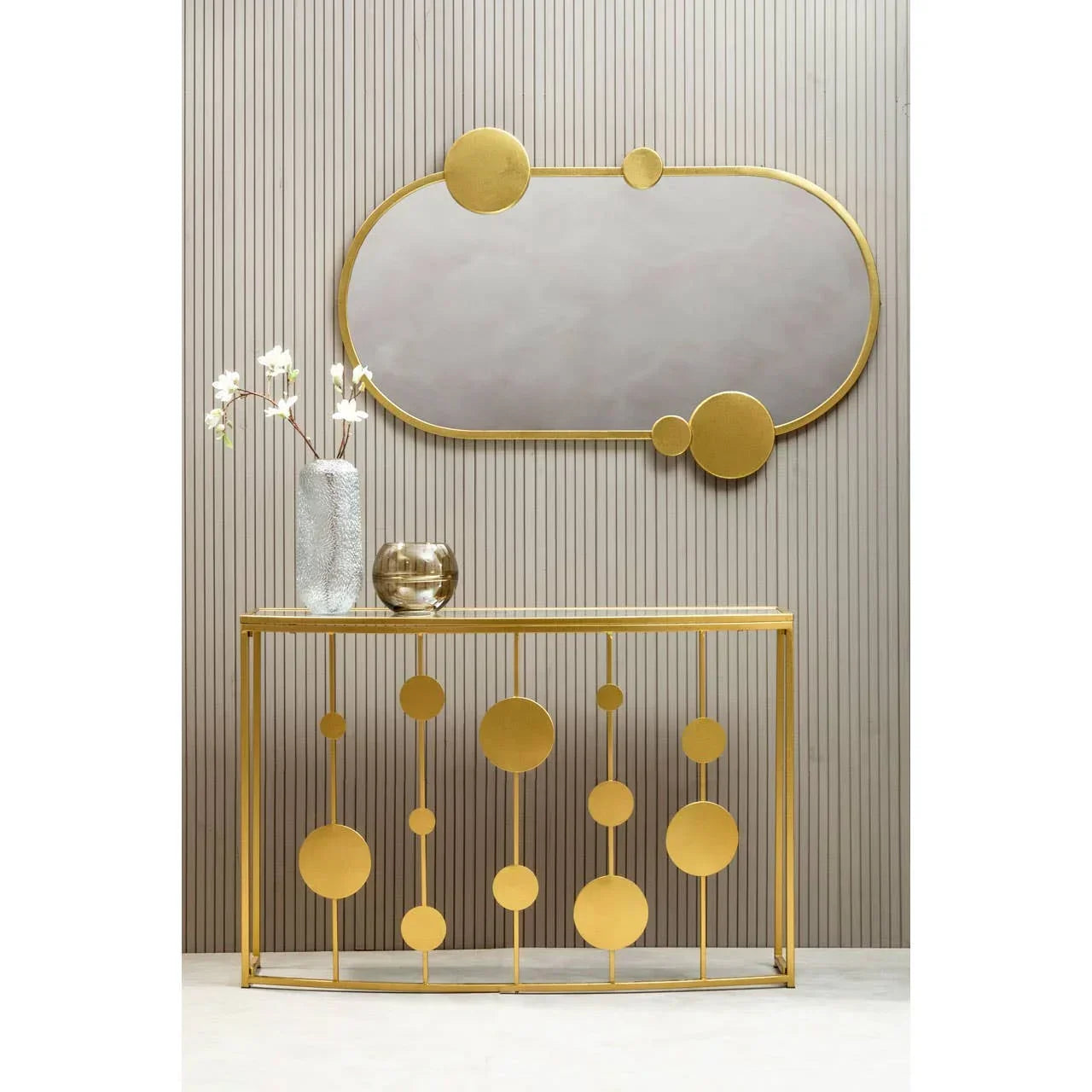 Gold console table with geometric circles and matching gold oval wall mirror in hallway setting