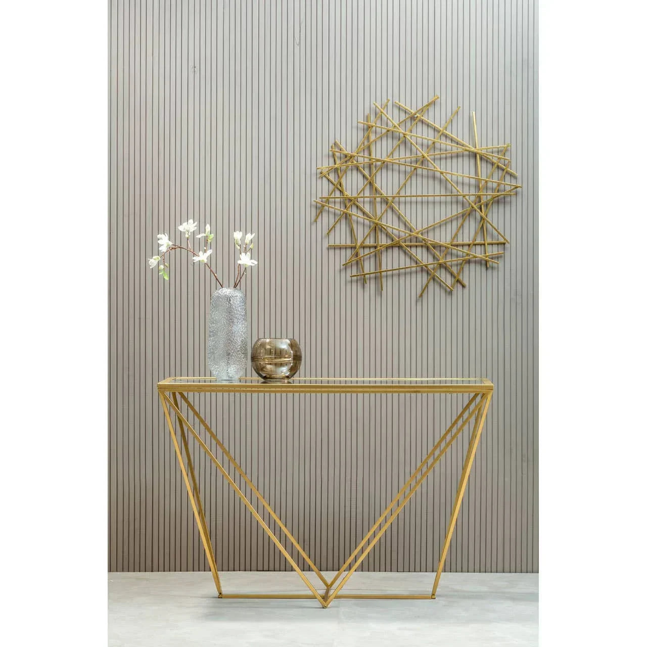 Gold metal console table with glass top, decorative vase and bowl, geometric wall art