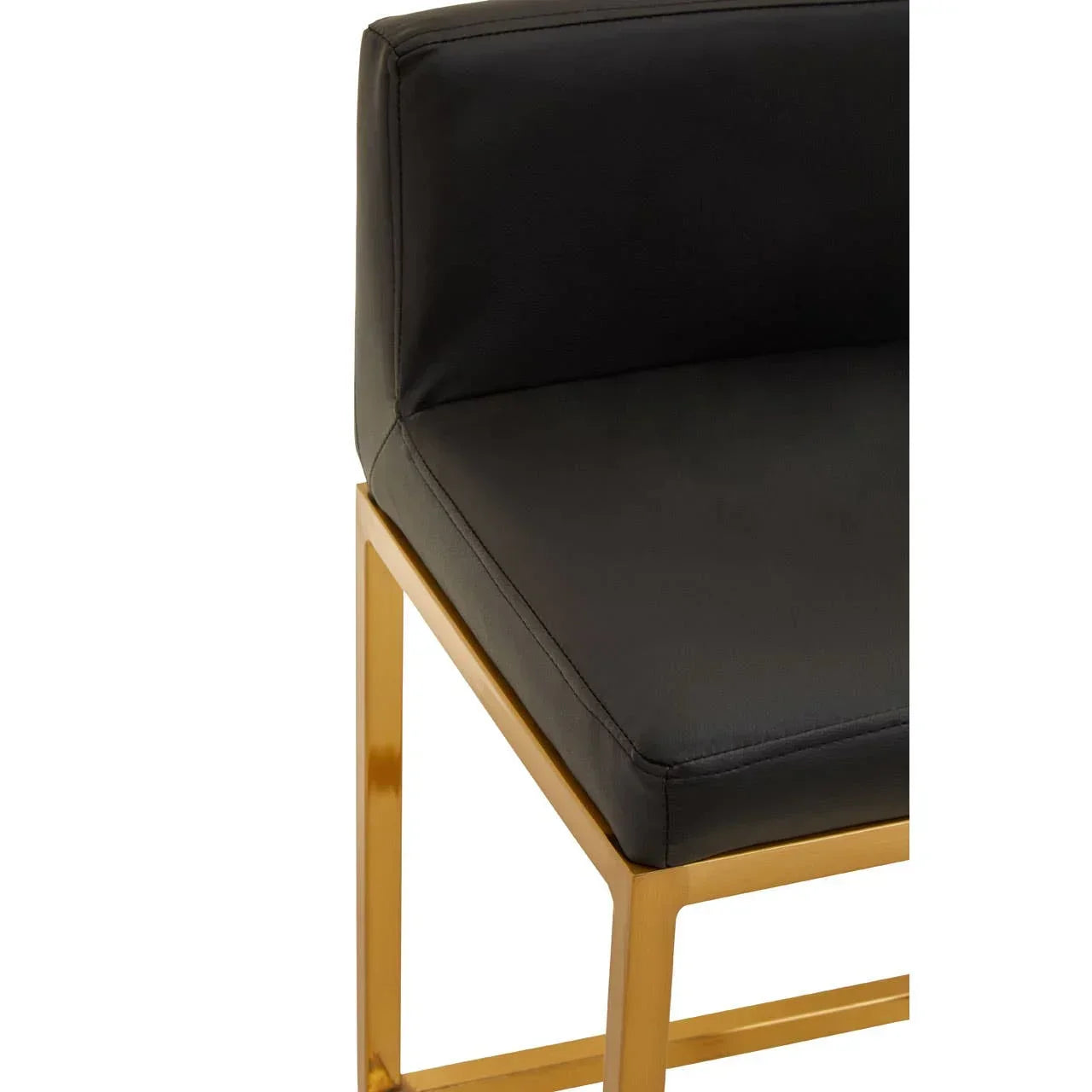 Black faux leather dining chair seat with gold metal frame, close-up of corner