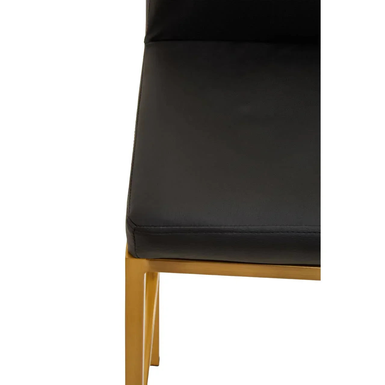 Black faux leather dining chair with gold metal legs, close-up view of seat and frame