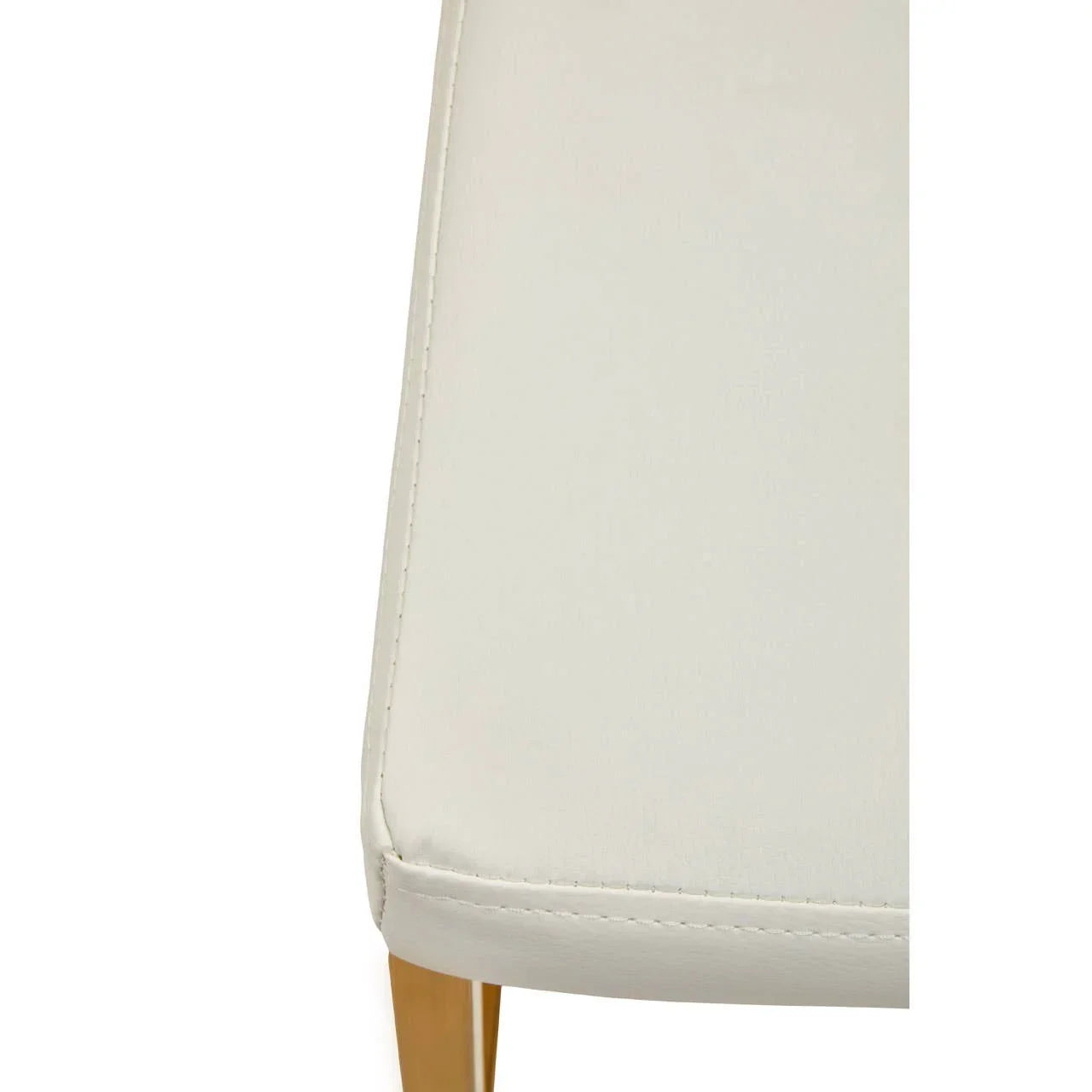 Close-up of cream leather dining chair seat with gold metal leg