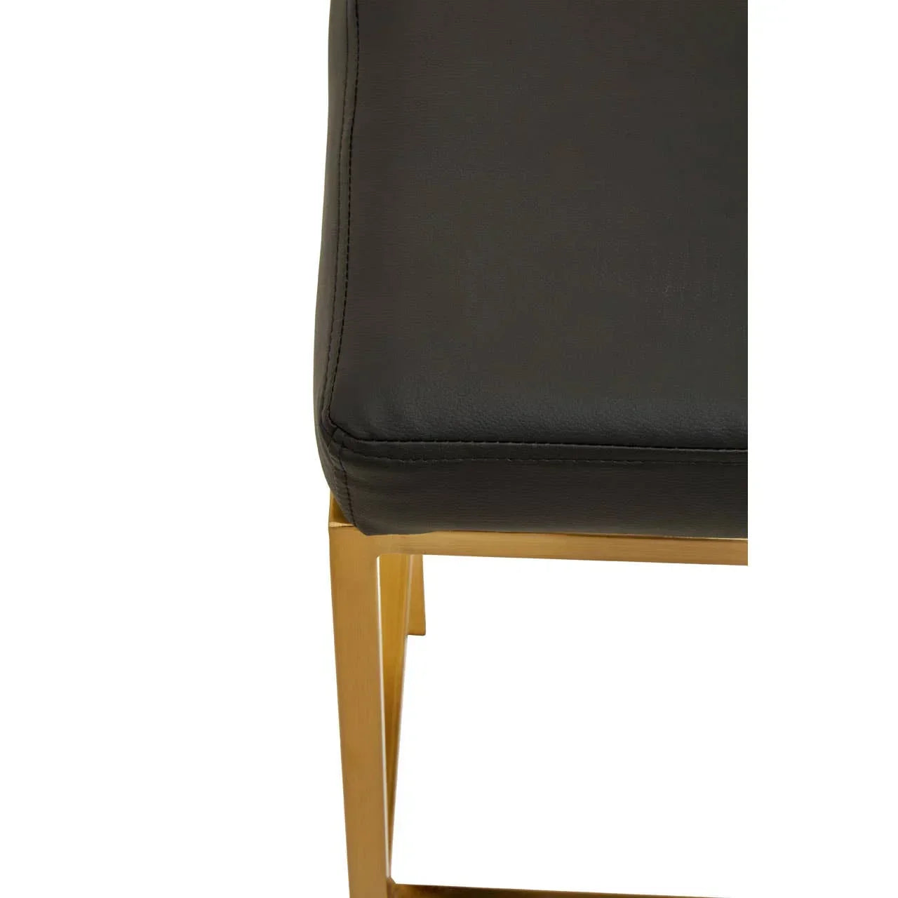 Corner of black leather dining chair with gold metal frame, close-up view