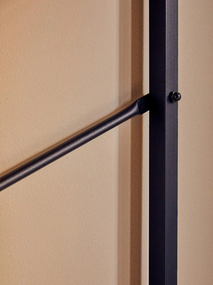 Close-up of black metal furniture frame against beige wall, featuring minimalist design