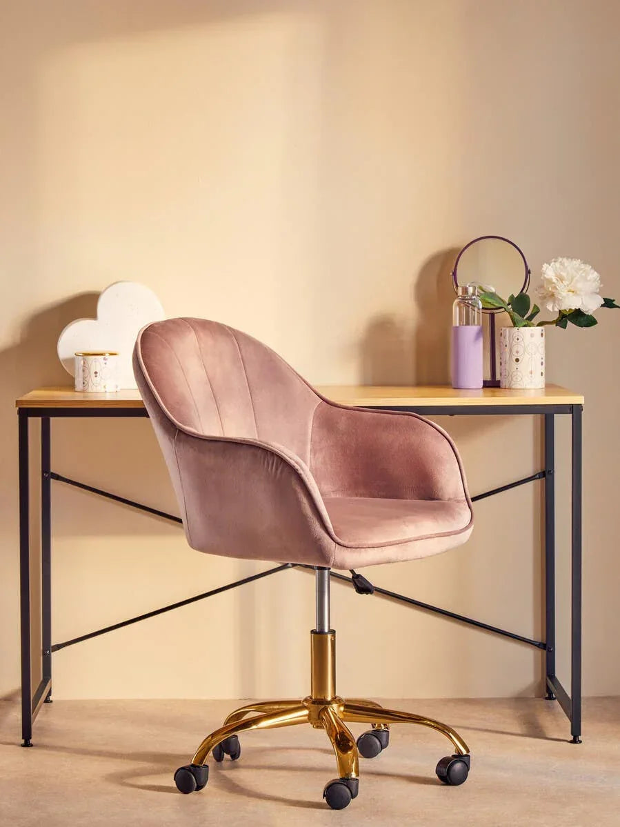 Blush pink velvet office chair with gold base at modern desk, floral decor and accessories
