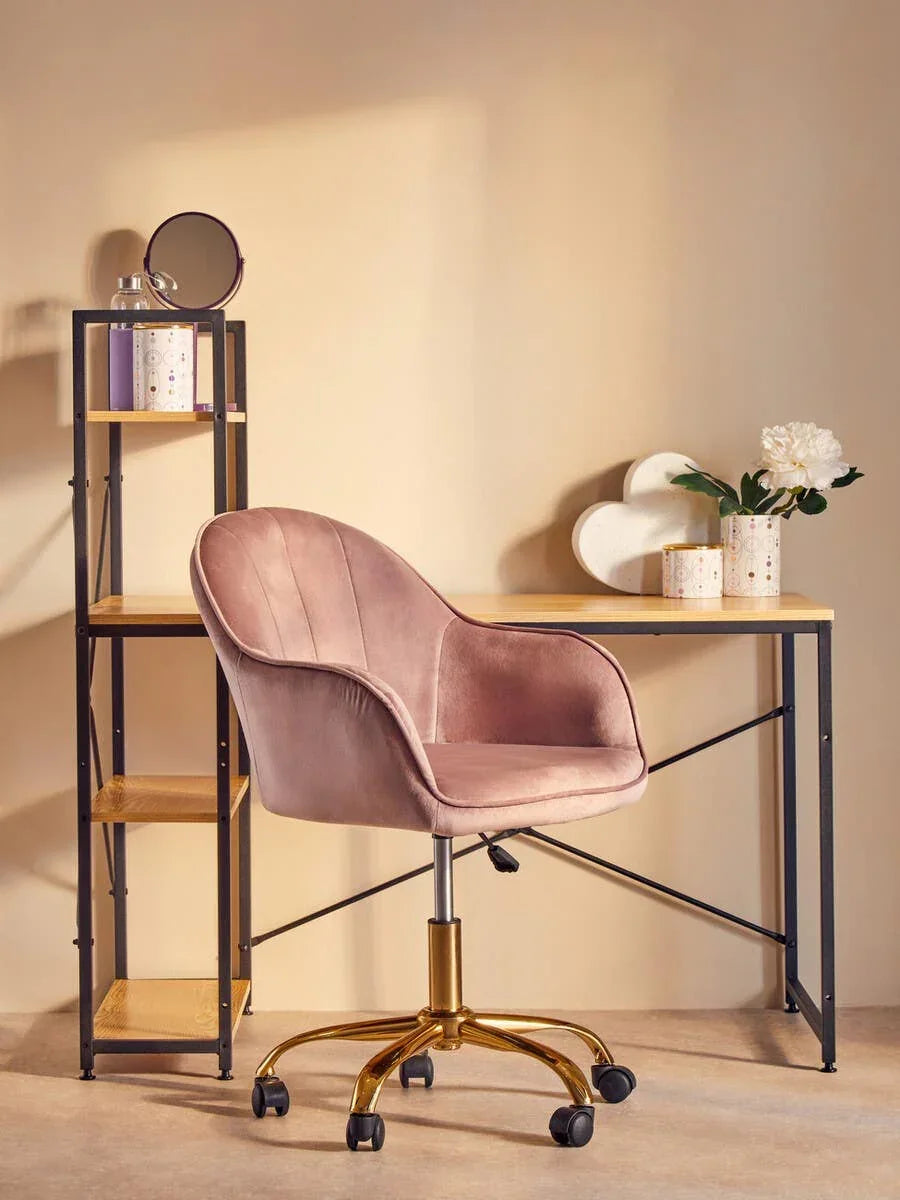 Pink velvet office chair with gold base at wooden desk and shelf unit