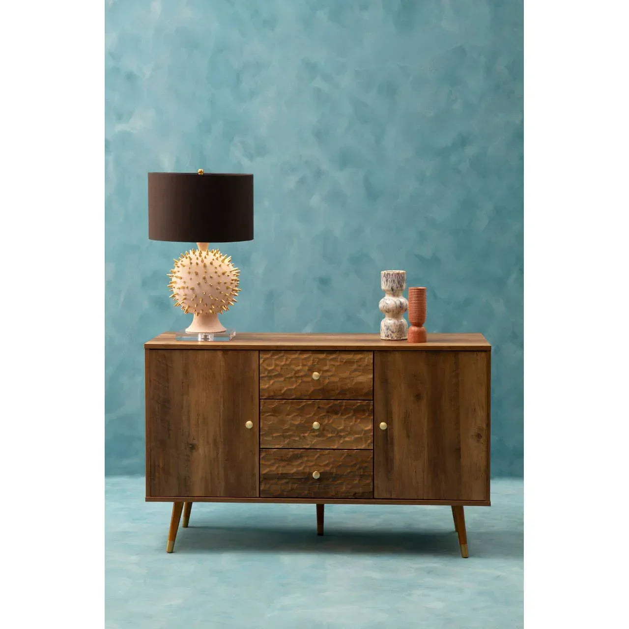 Mid-century wood sideboard with textured drawers, black lampshade and decorative vases