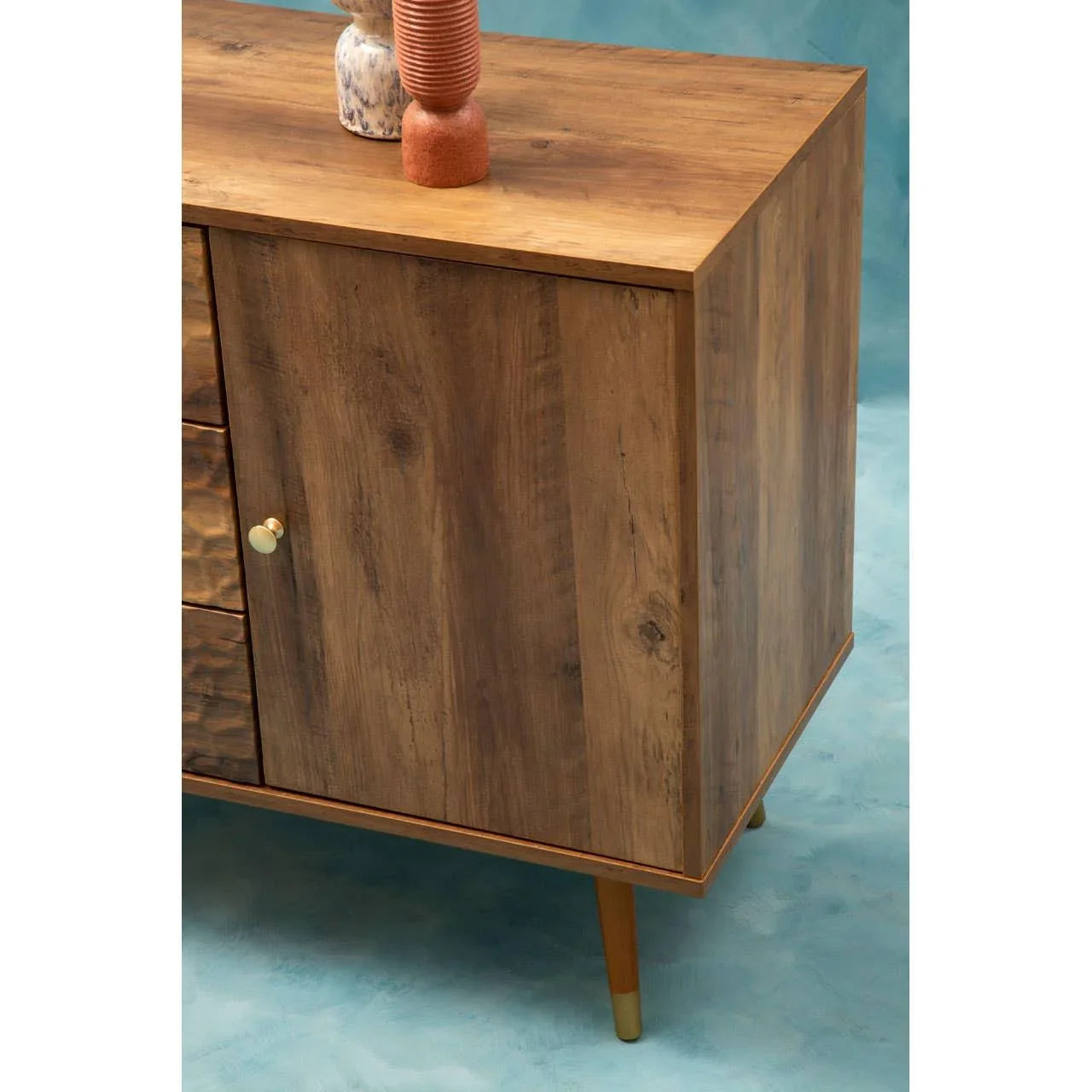 Mid-century wood sideboard with gold knob and angled legs on blue background