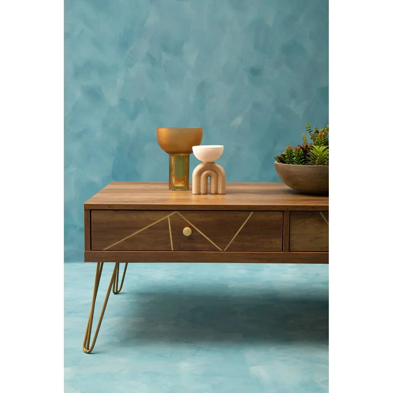 Modern wood coffee table with gold accents and decor against blue wall