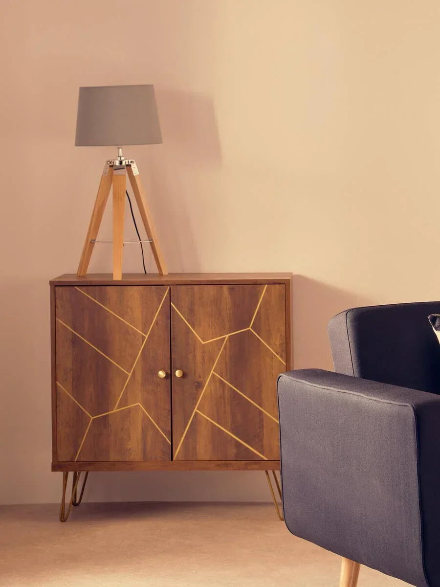 Wooden sideboard with gold geometric accents, tripod lamp, and dark grey armchair