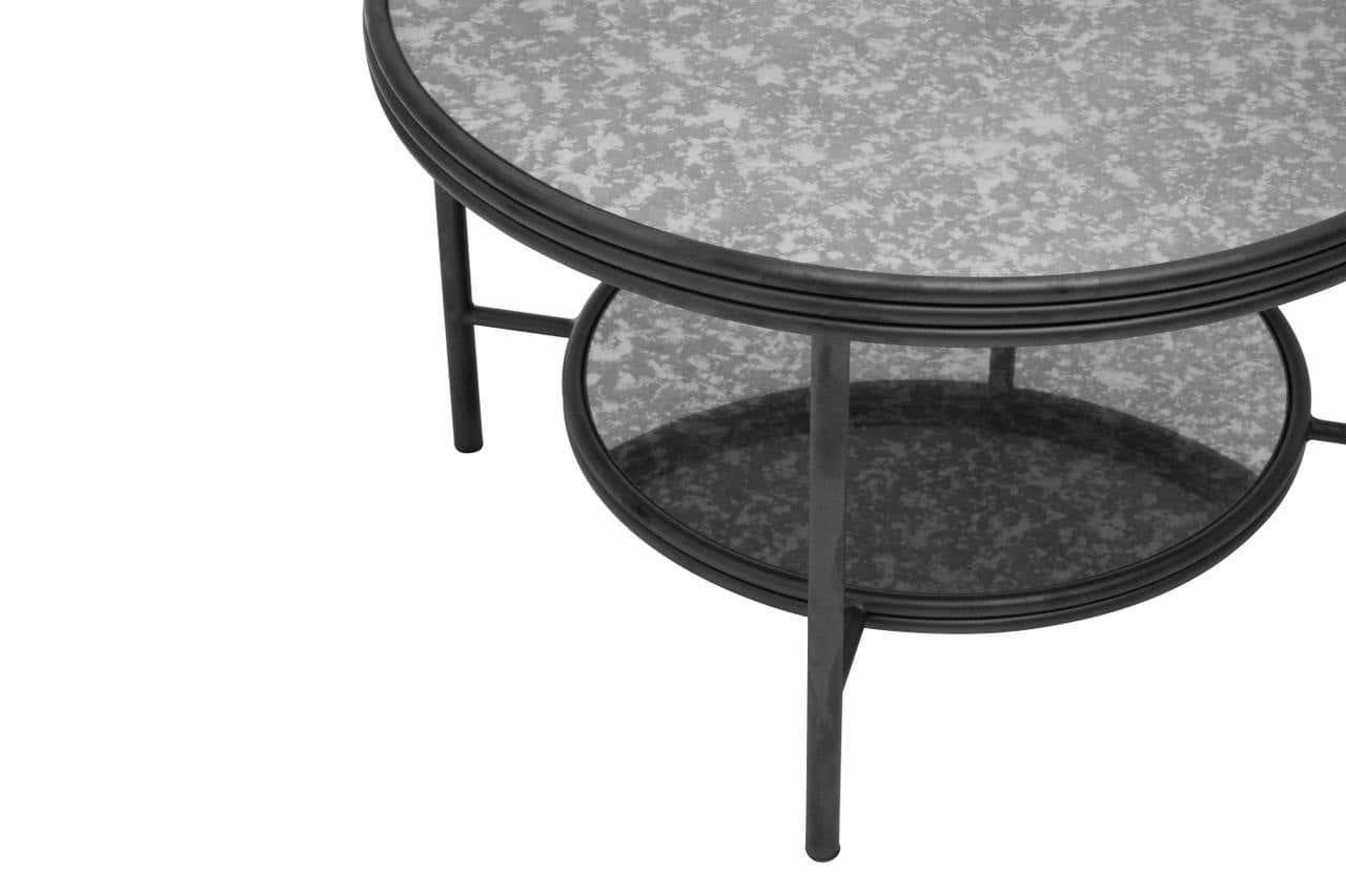 Round glass coffee table with black metal frame and lower shelf, close-up side angle