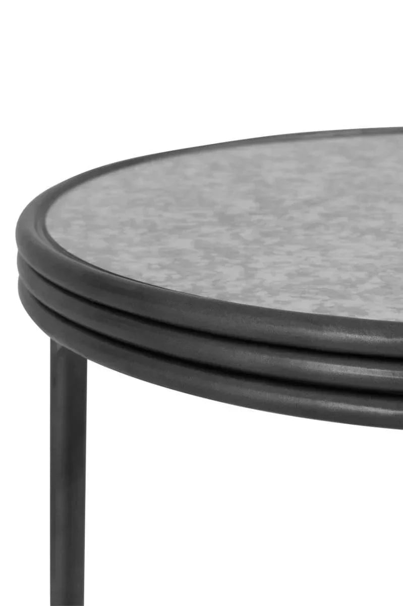 Round metal side table with textured grey tabletop and black frame, close-up view