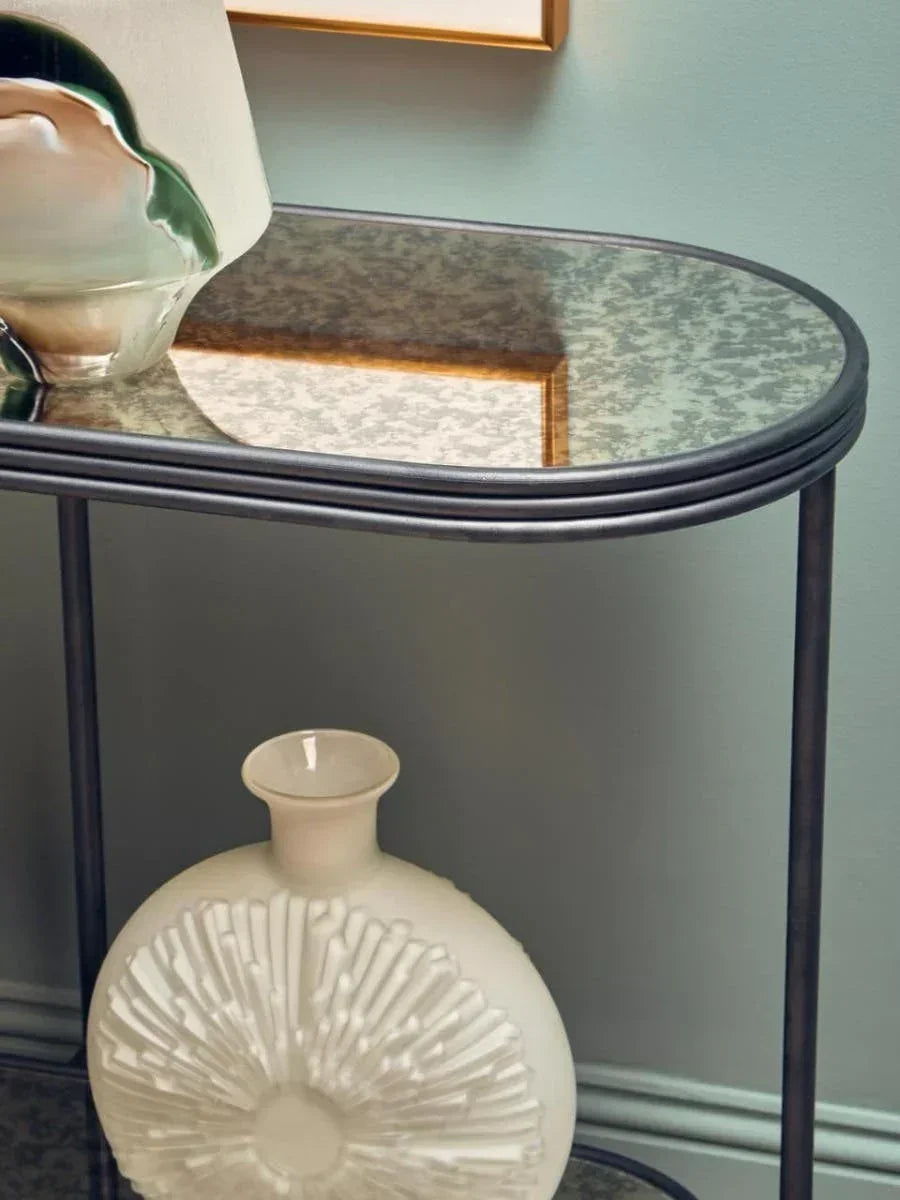 Glass console table with black metal frame, decorative ceramic vase and abstract lamp