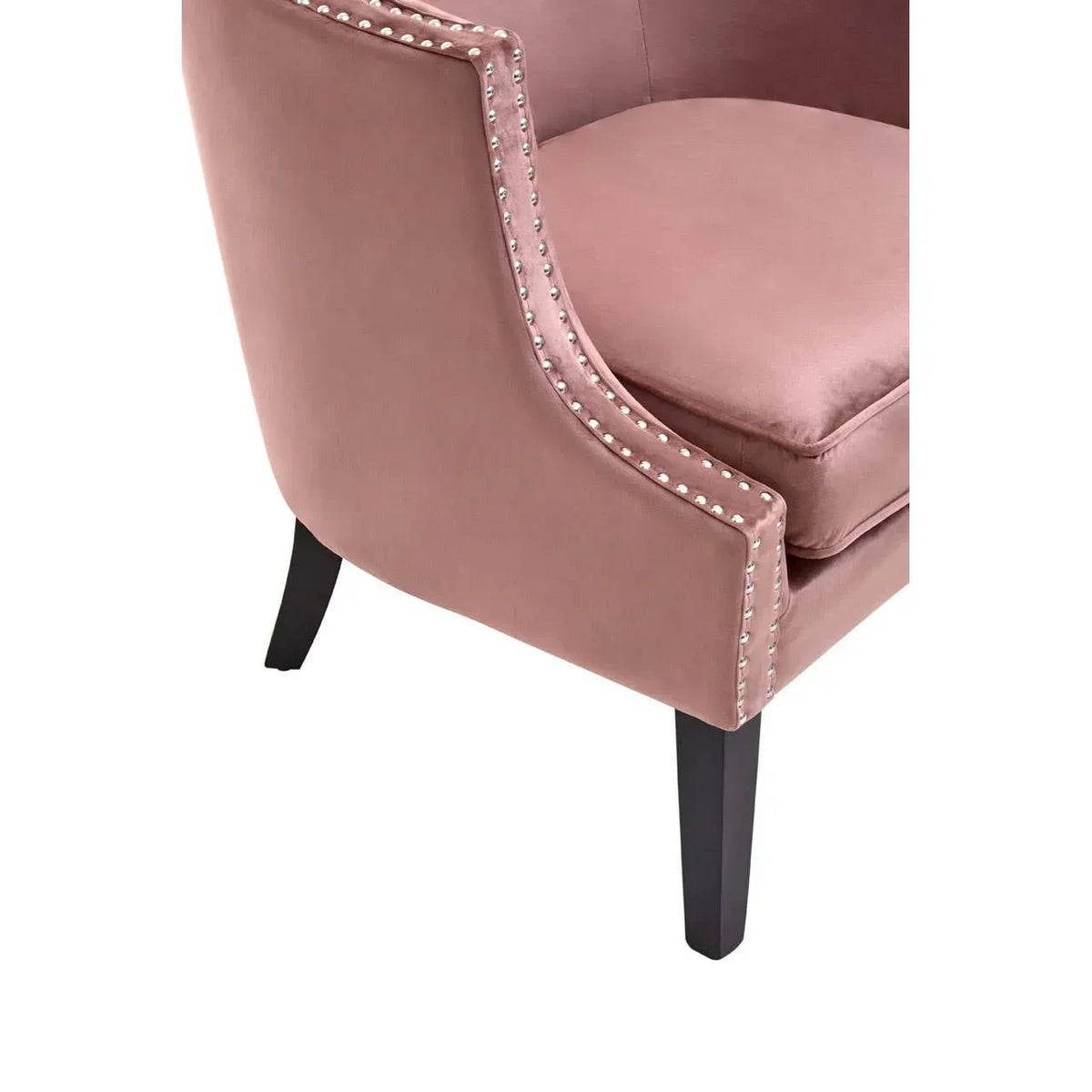 Pink velvet accent chair with silver stud detailing and black wooden legs, side angle view