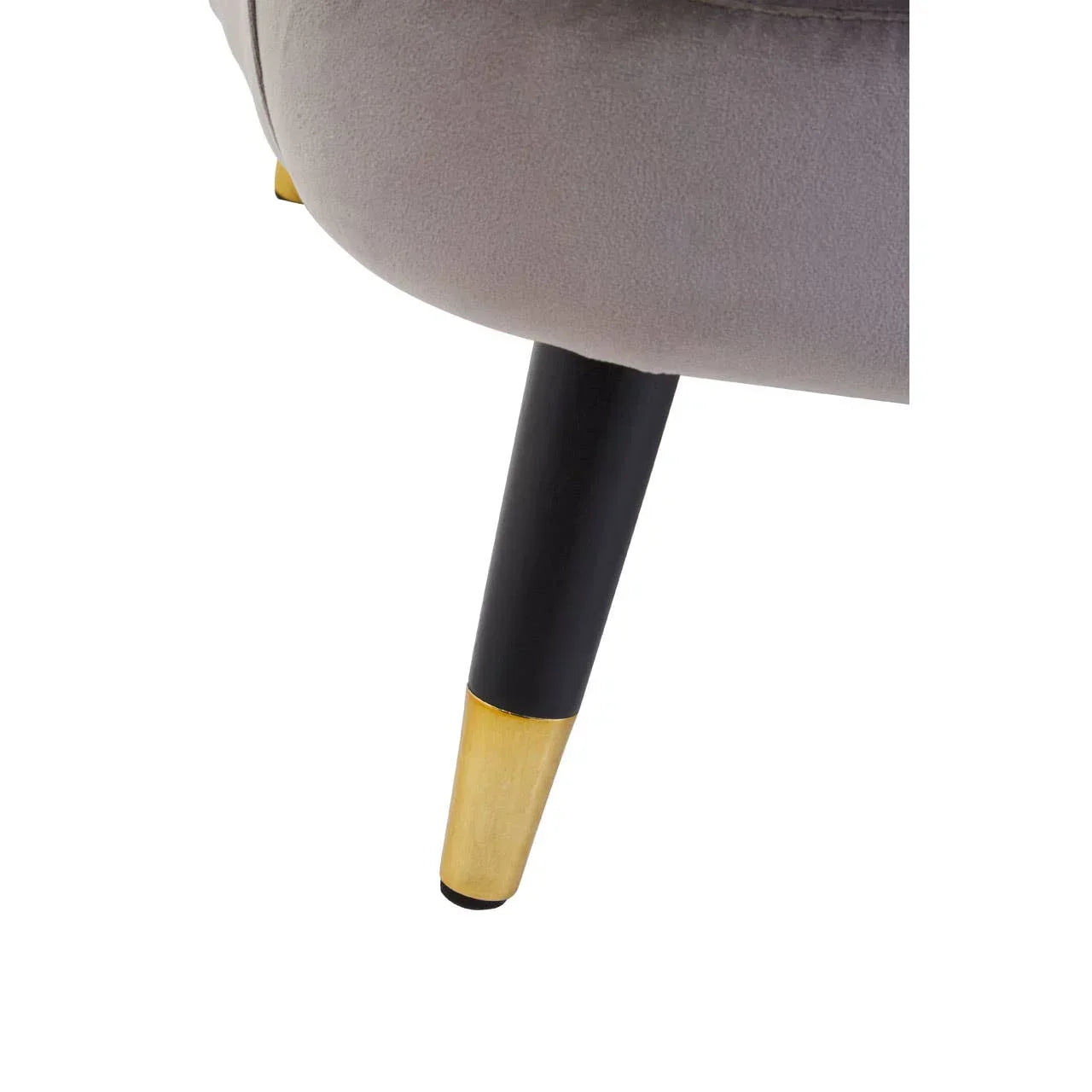 Grey upholstered chair with black and gold tapered metal leg close-up