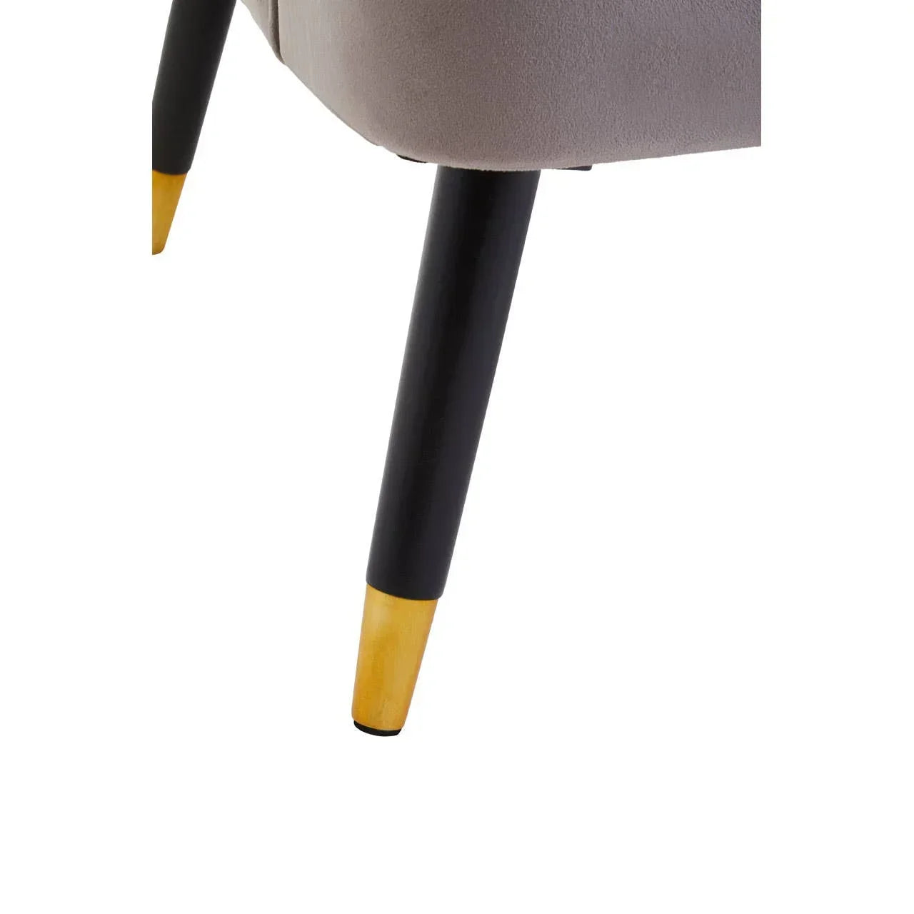 Close up of chair leg with black and gold finish attached to grey upholstered seat