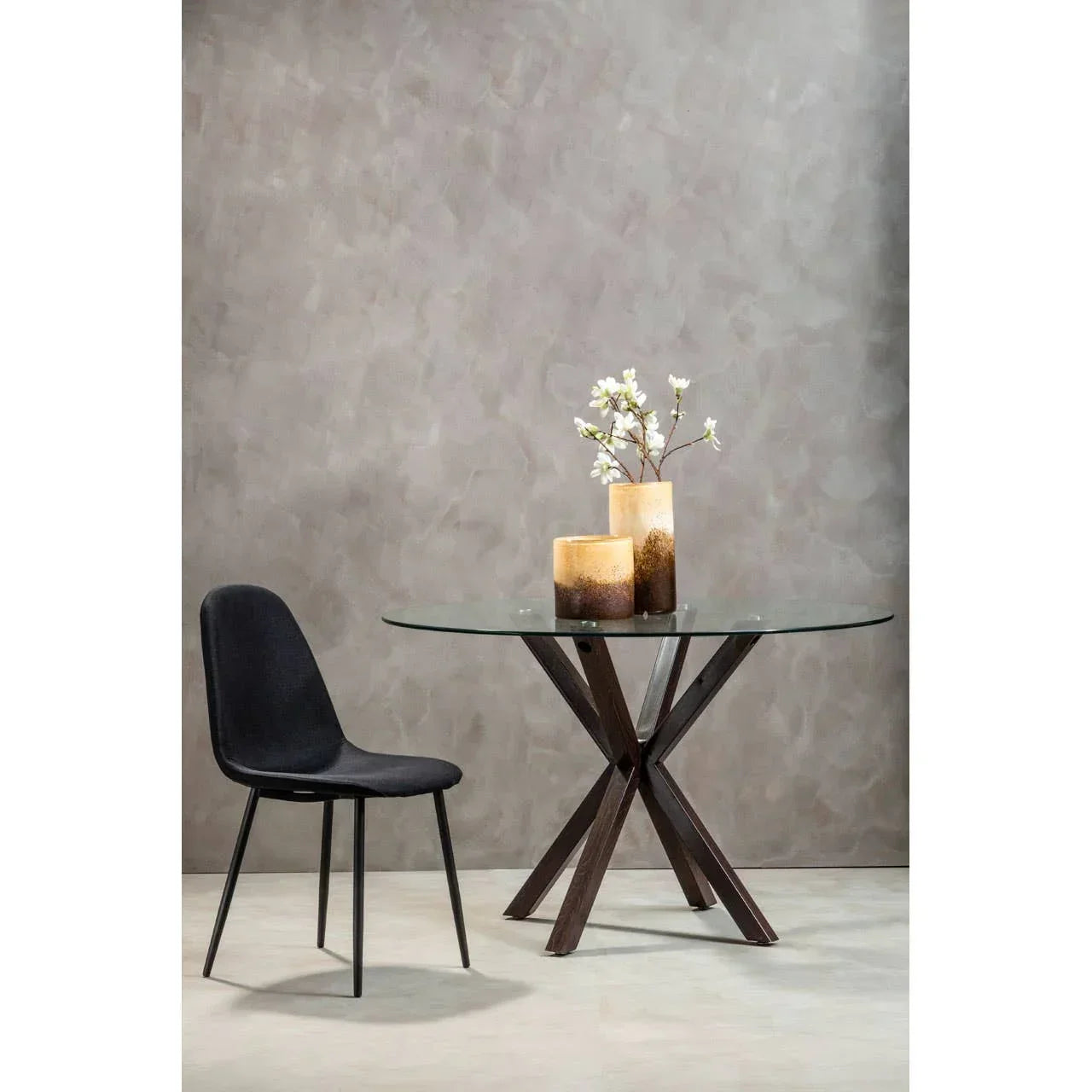 Glass dining table with wooden legs and black chair, decorative vases and flowers on top