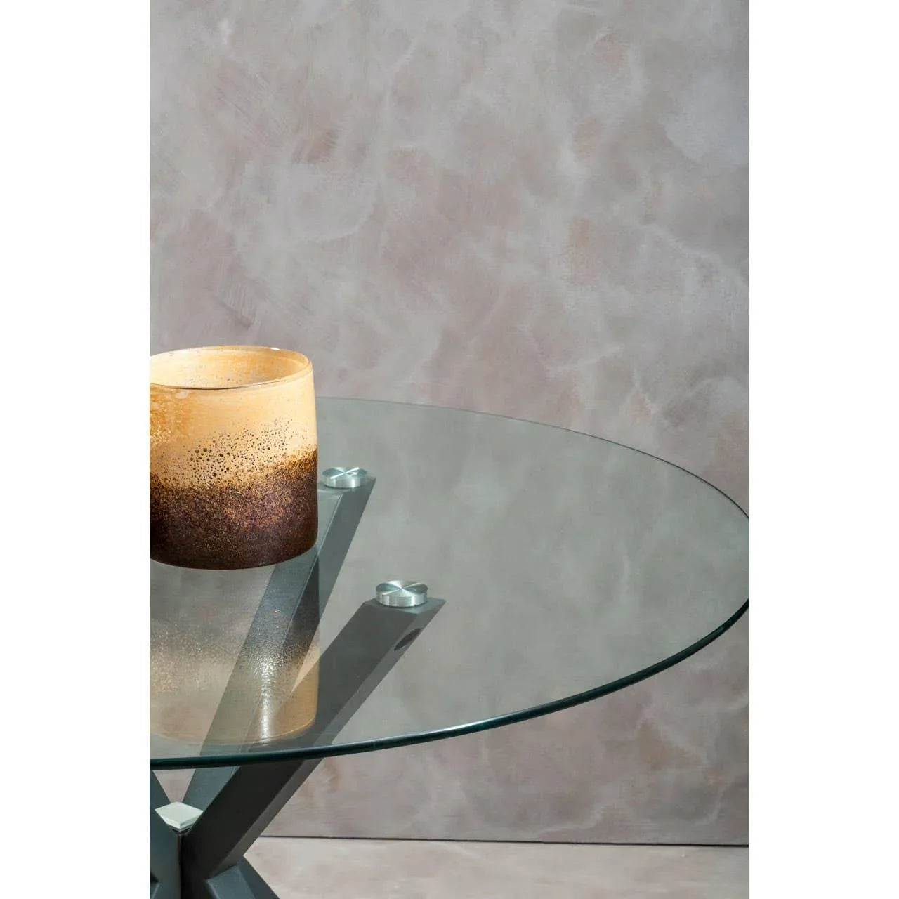 Round glass dining table with metal legs and brown decorative vase on top