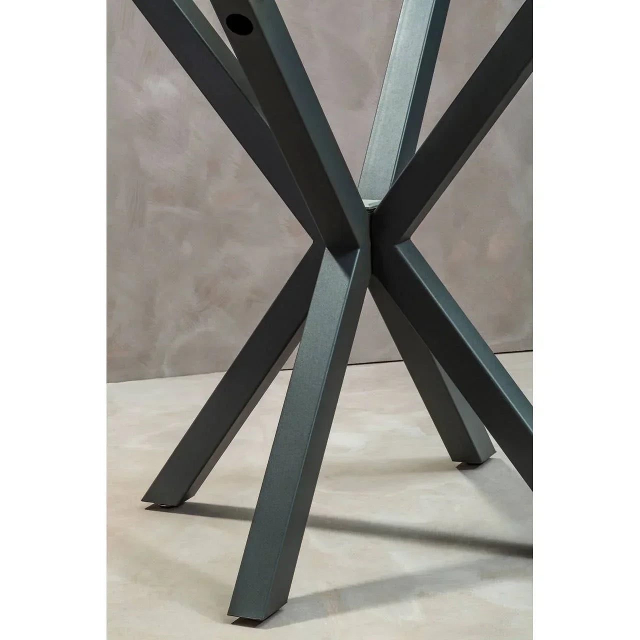 Black metal dining table legs with a modern cross design on neutral floor