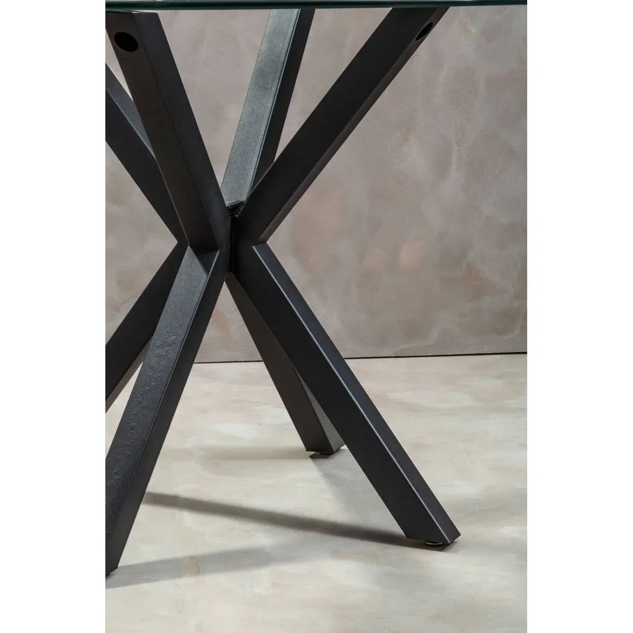 Black metal dining table legs with crossed design and glass tabletop corner