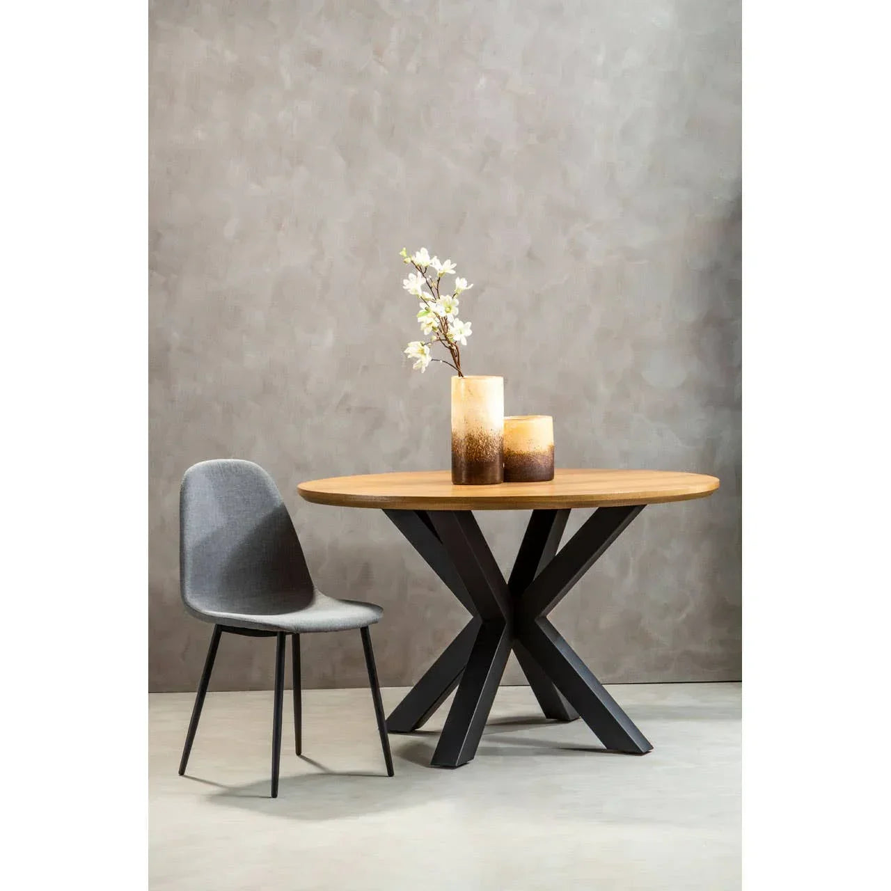 Round oak dining table with black metal legs, grey chair and decorative vases