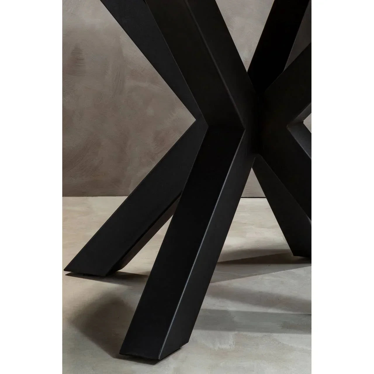 Black metal dining table base with cross-leg design on neutral floor