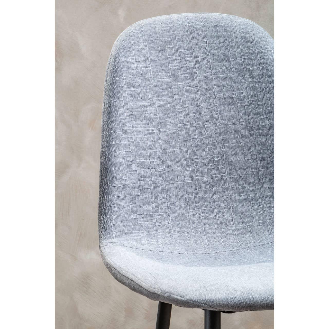 Light grey fabric dining chair with curved backrest and black metal legs, close-up view