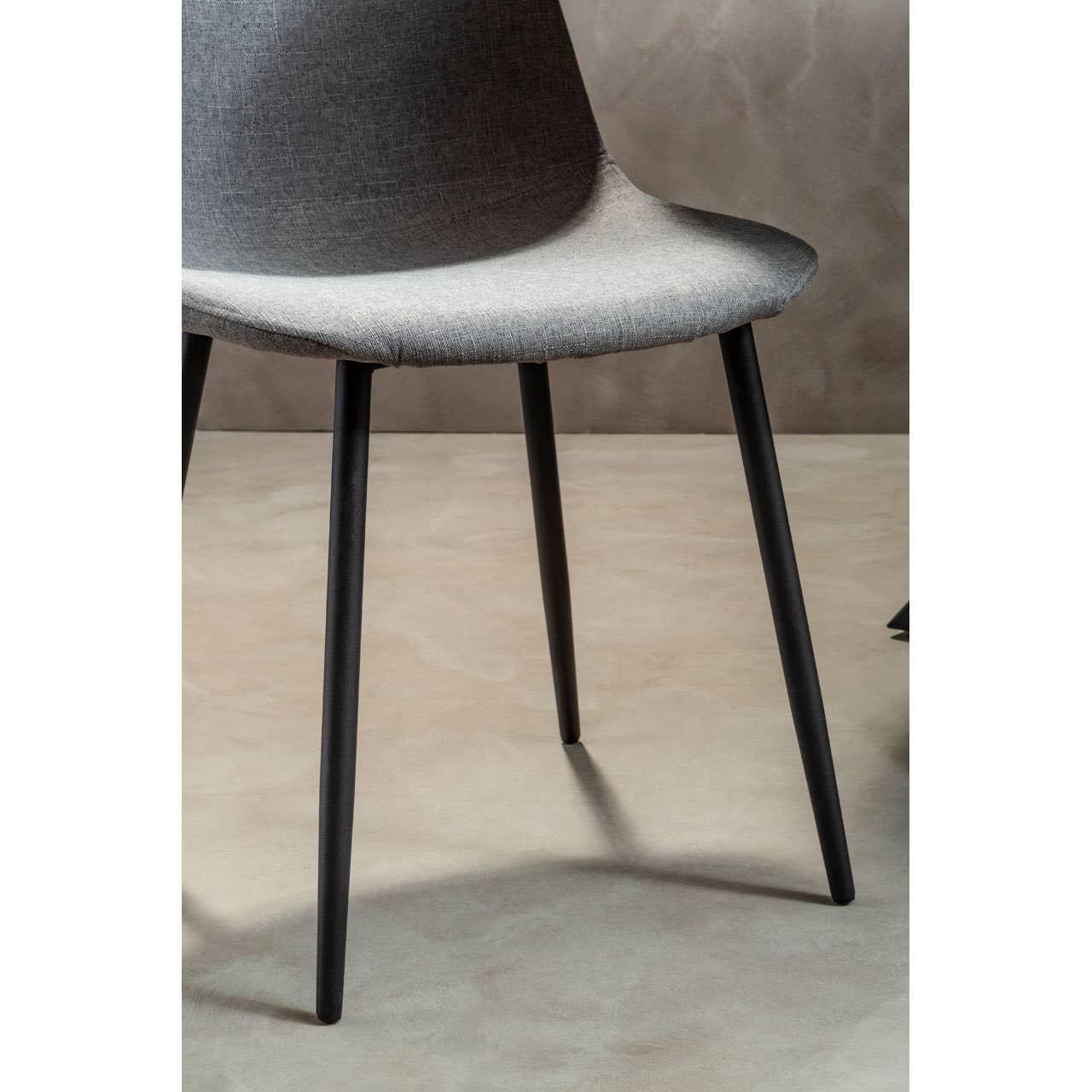 Grey fabric dining chair with curved seat and black metal legs on neutral floor