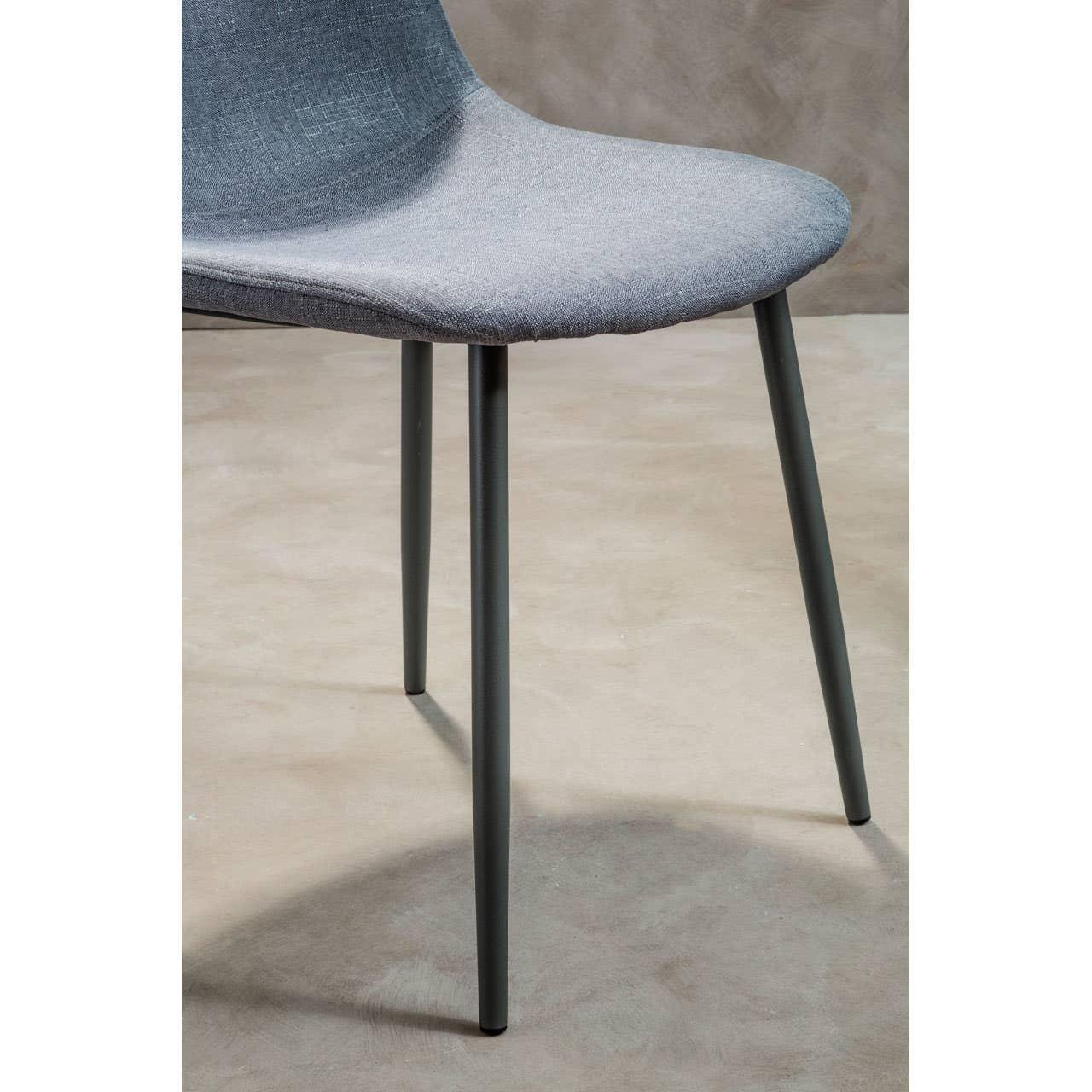 Grey fabric dining chair with metal legs on concrete floor, close-up of seat and legs