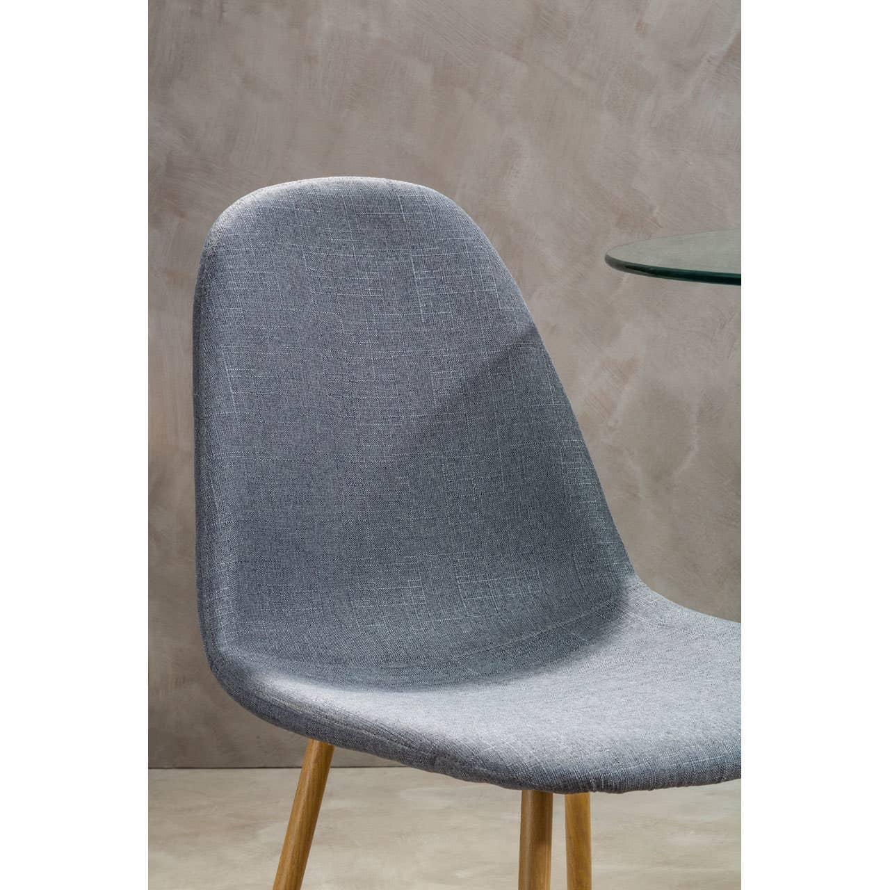 Grey fabric dining chair with wooden legs beside a glass table