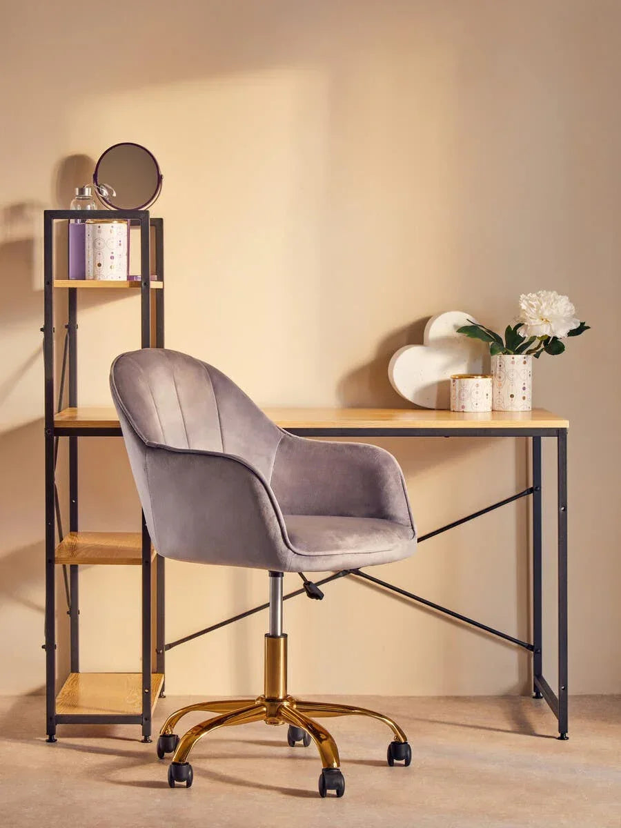 Grey velvet office chair with gold legs at wooden desk and shelving unit with decor items