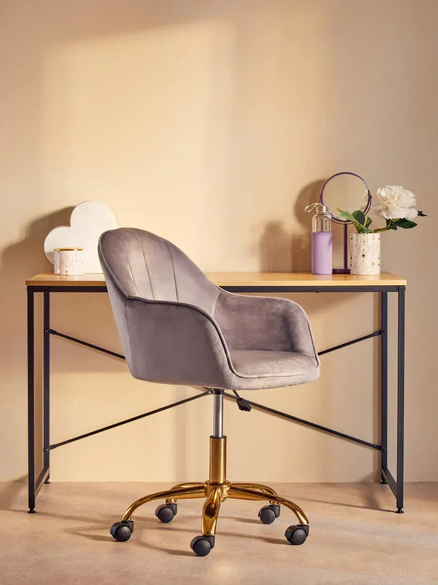 Grey velvet office chair with gold base at modern writing desk, decor and flower vase on top